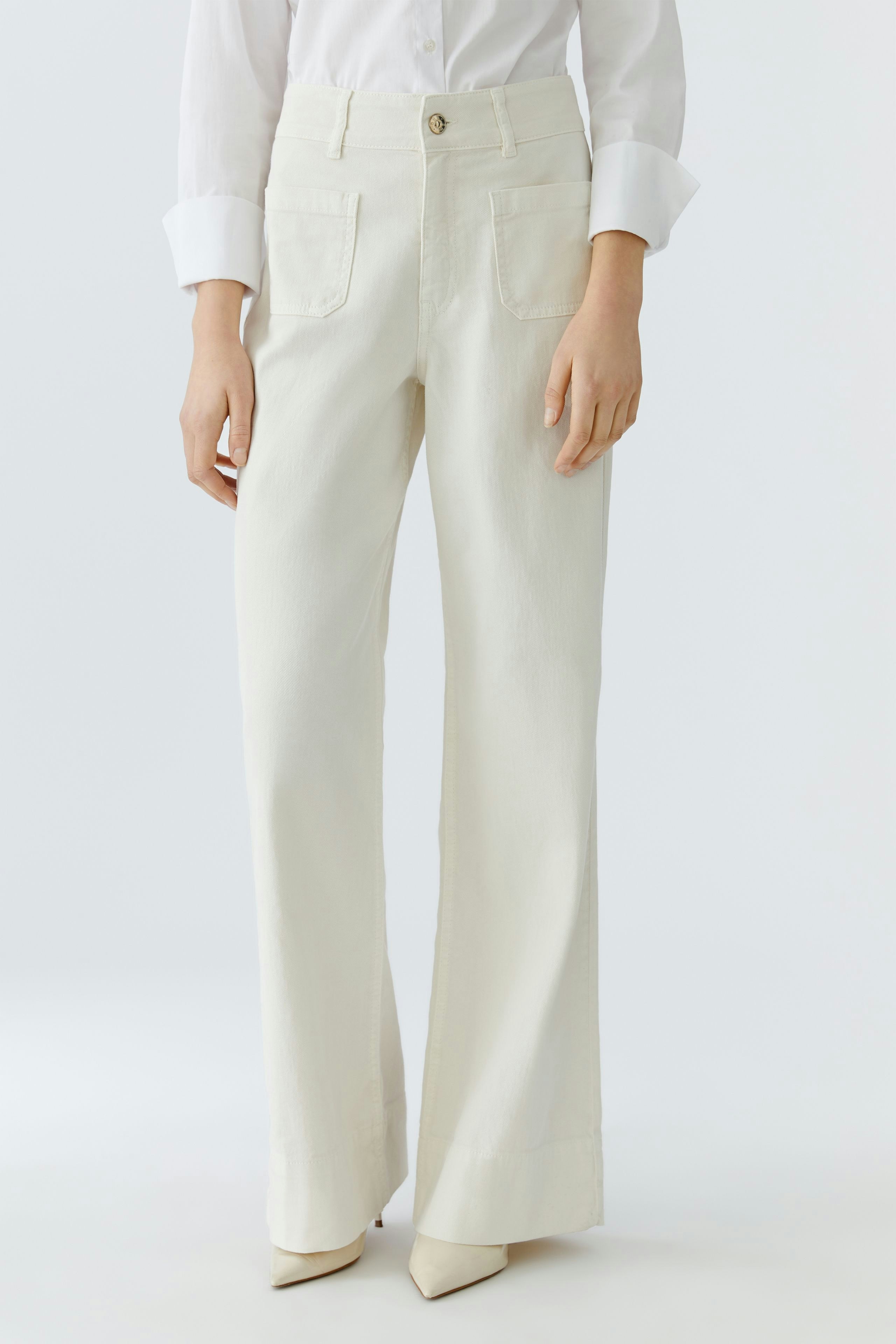 Wide leg jeans for women: A woman in cream-colored wide leg jeans paired with a white shirt.