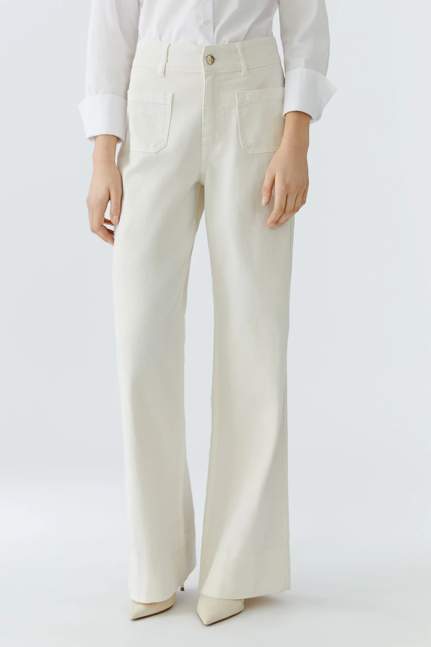 Wide leg jeans for women: A woman in cream-colored wide leg jeans paired with a white shirt.