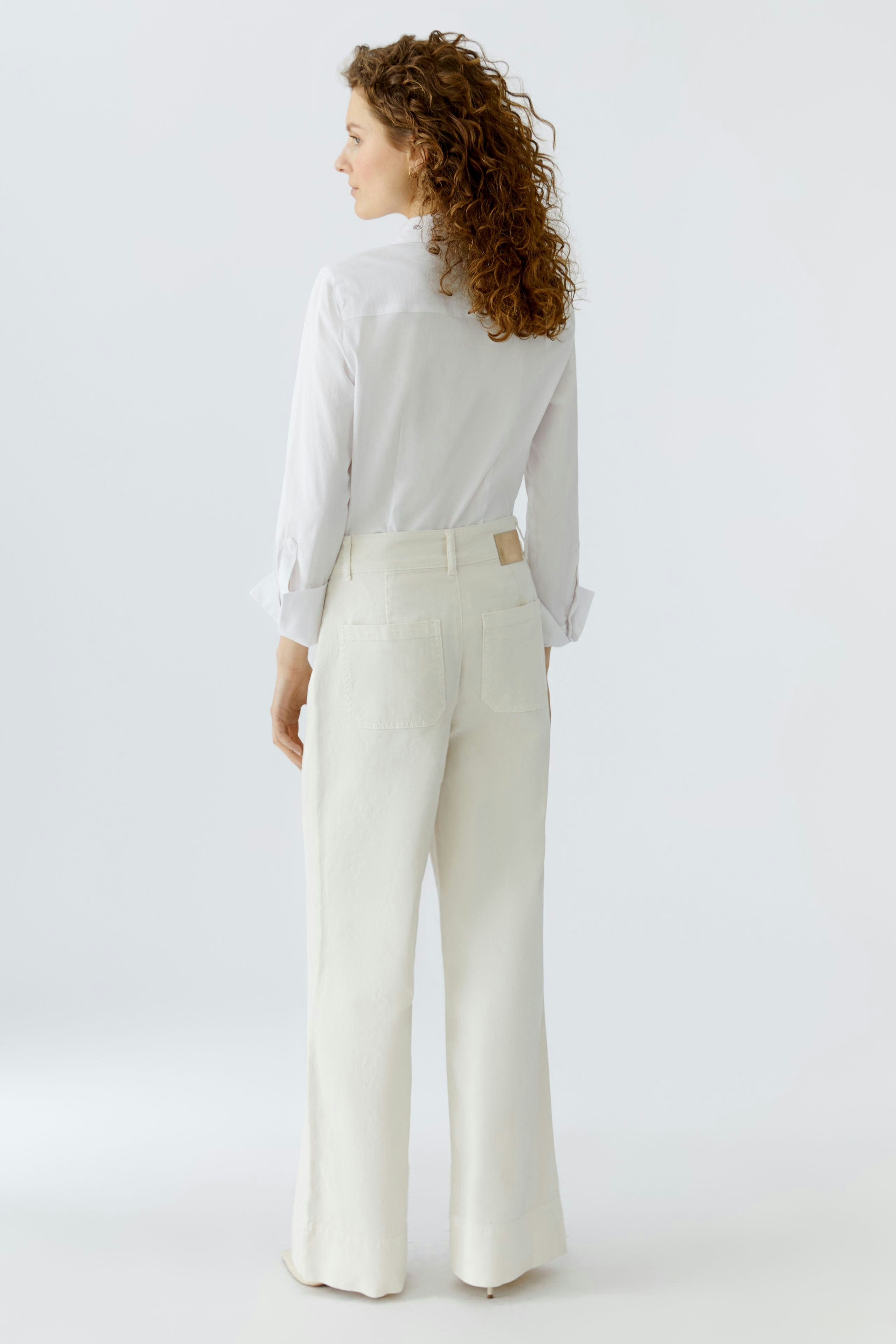 Wide leg jeans: Woman in white wide leg jeans and a white shirt, showcasing a relaxed fit.