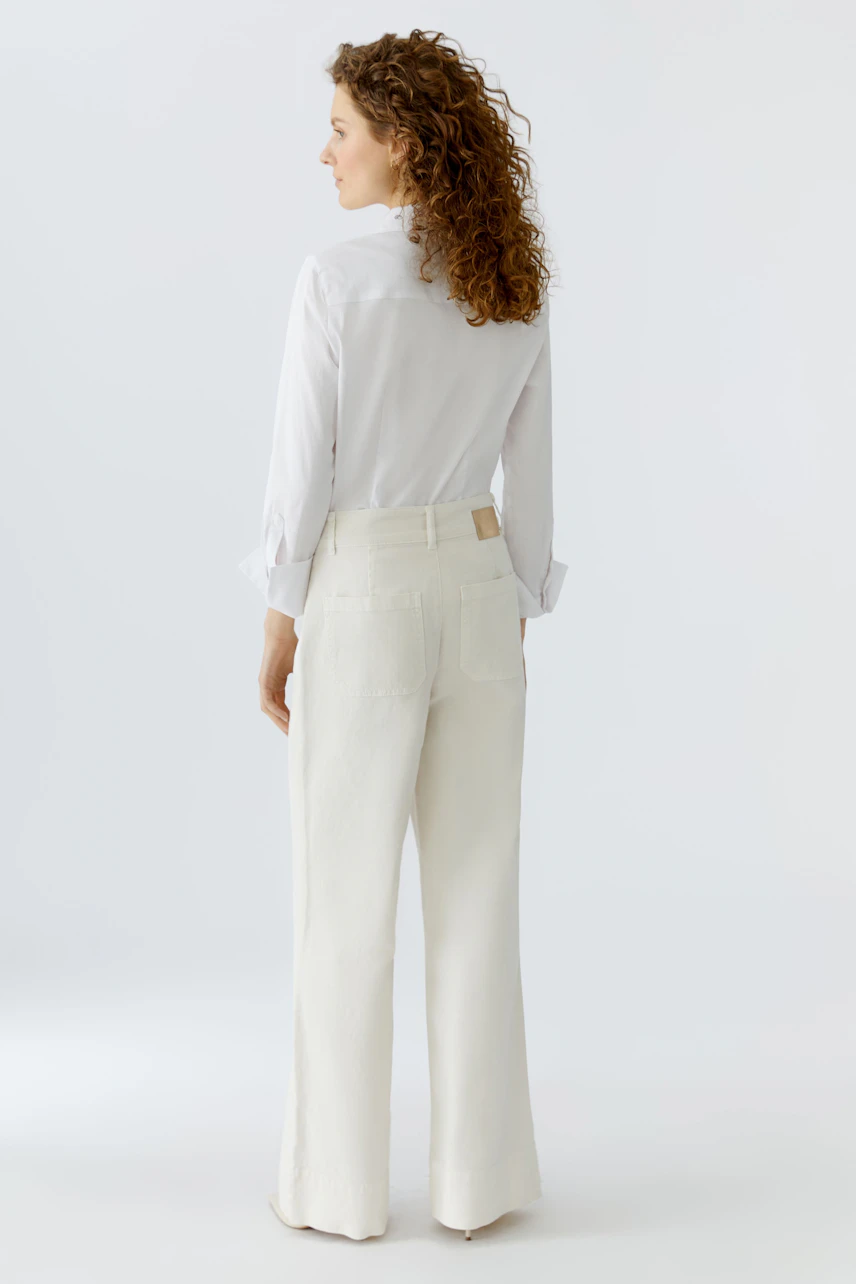 Wide leg jeans: Woman in white wide leg jeans and a white shirt, showcasing a relaxed fit.