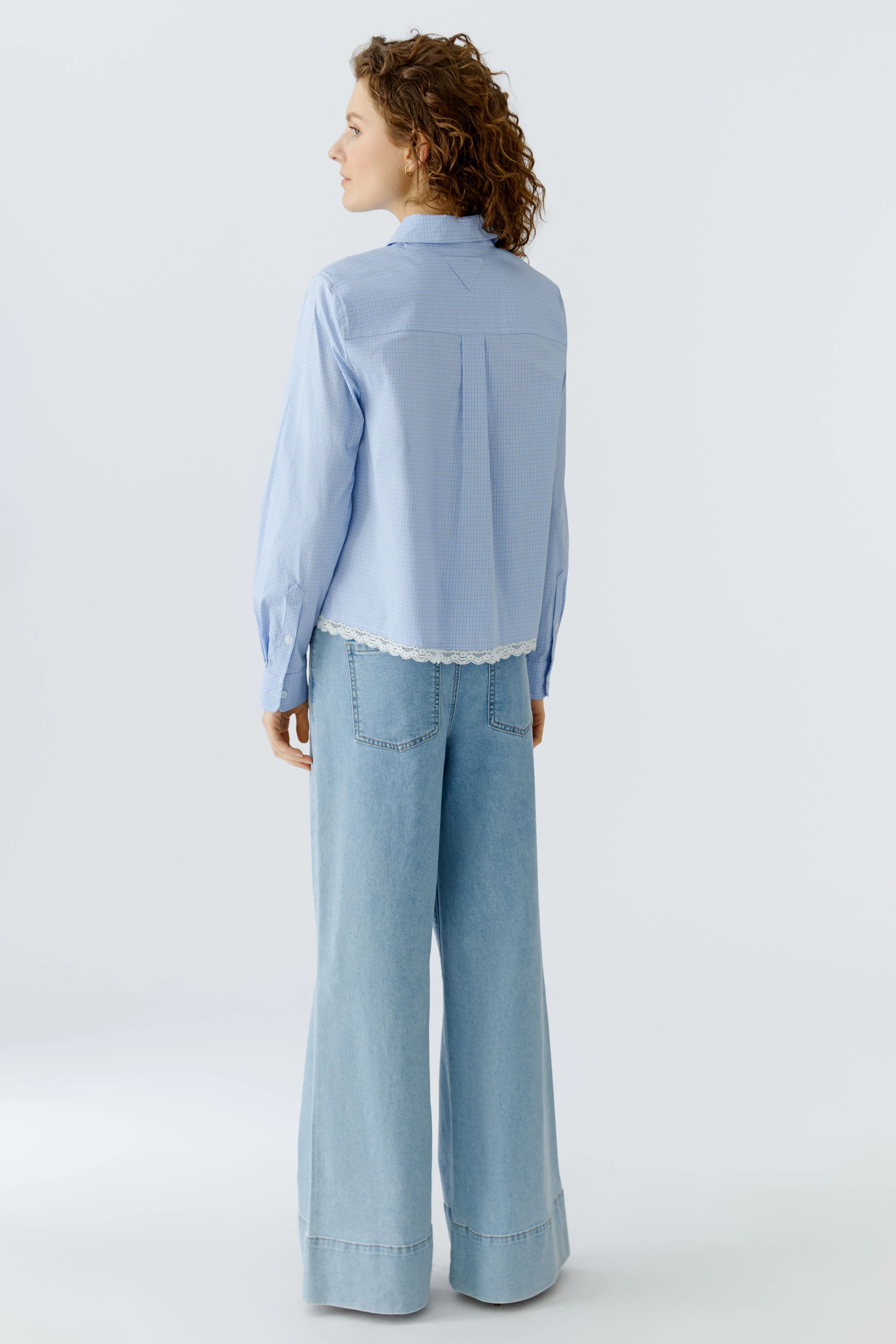 Casual women's shirt blouse: A woman in a light blue shirt with a lace hem and relaxed fit.