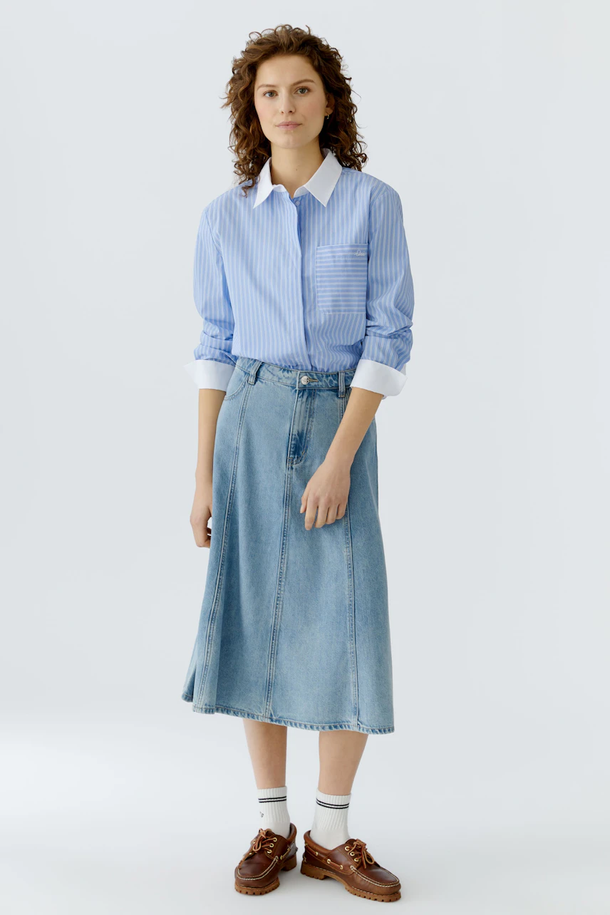 Casual women's blouse: Woman in a blue striped blouse with a white collar, paired with a denim skirt.