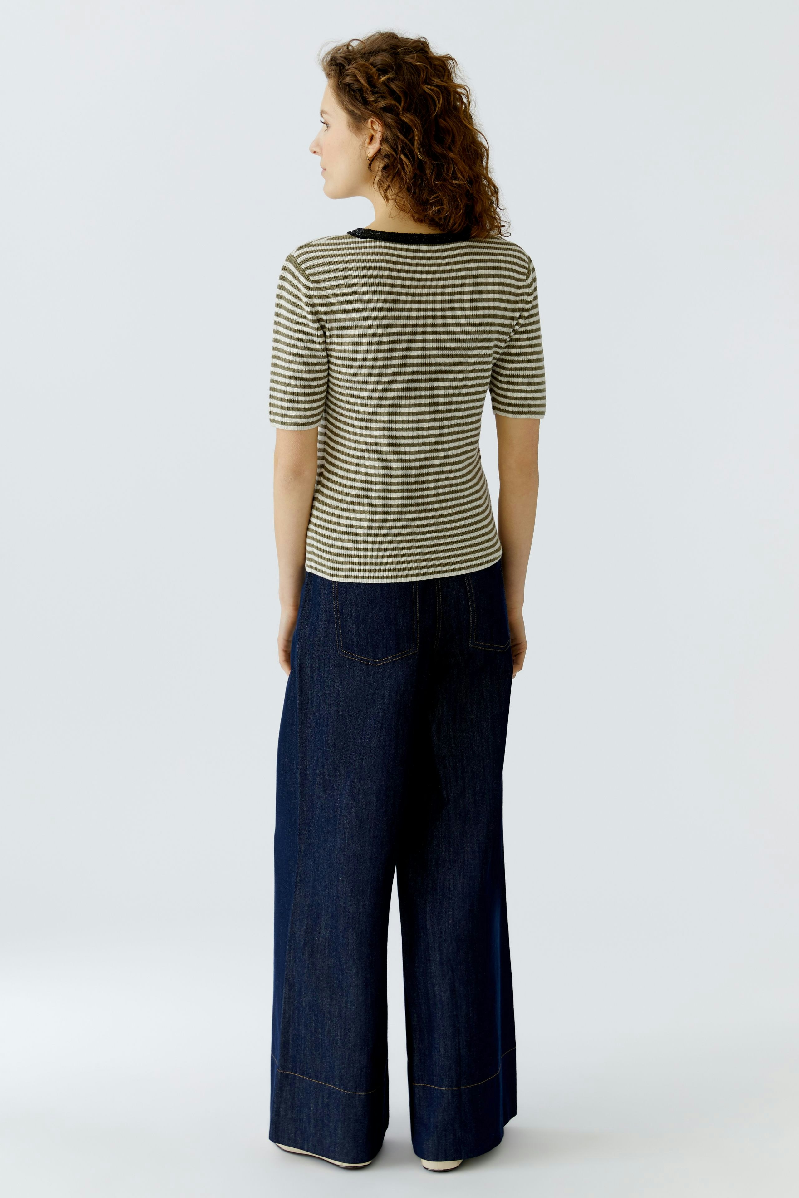 Casual women's pullover: A woman in a striped pullover and wide-leg jeans stands confidently.