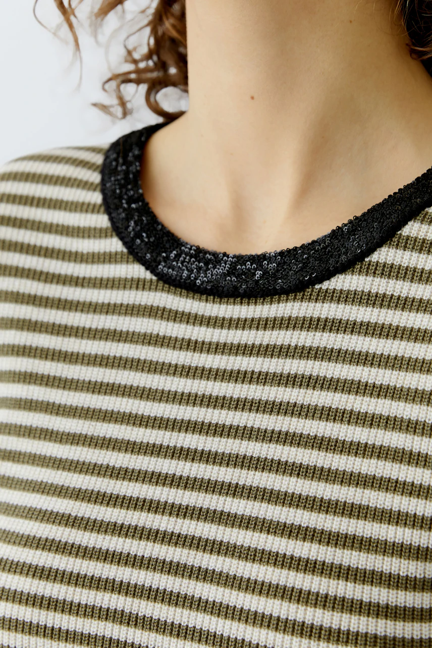 Casual women's pullover: Close-up of a striped pullover with a black sequin neckline.