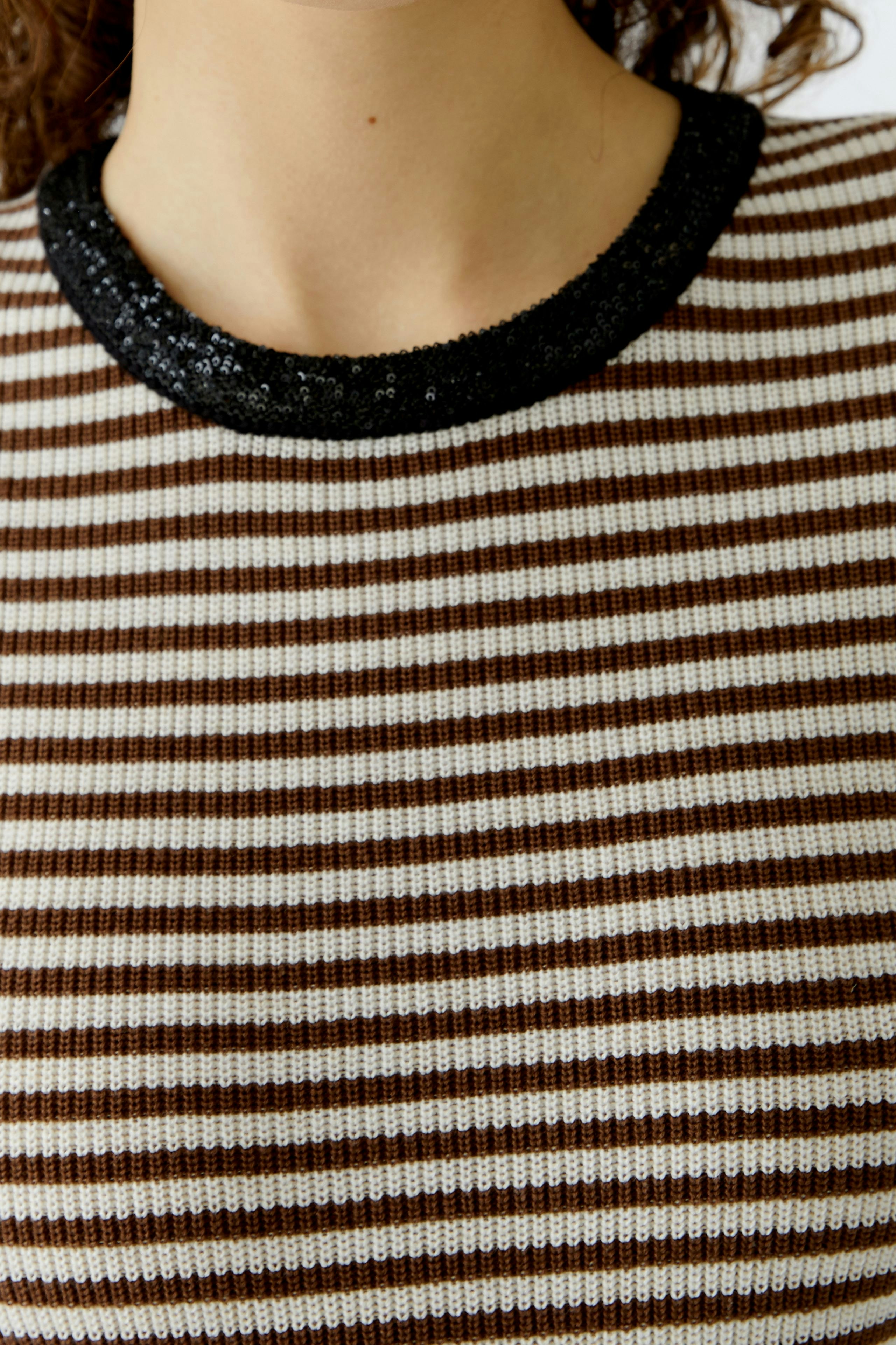 Casual women's pullover: Close-up of a striped pullover with a black sequined neckline.