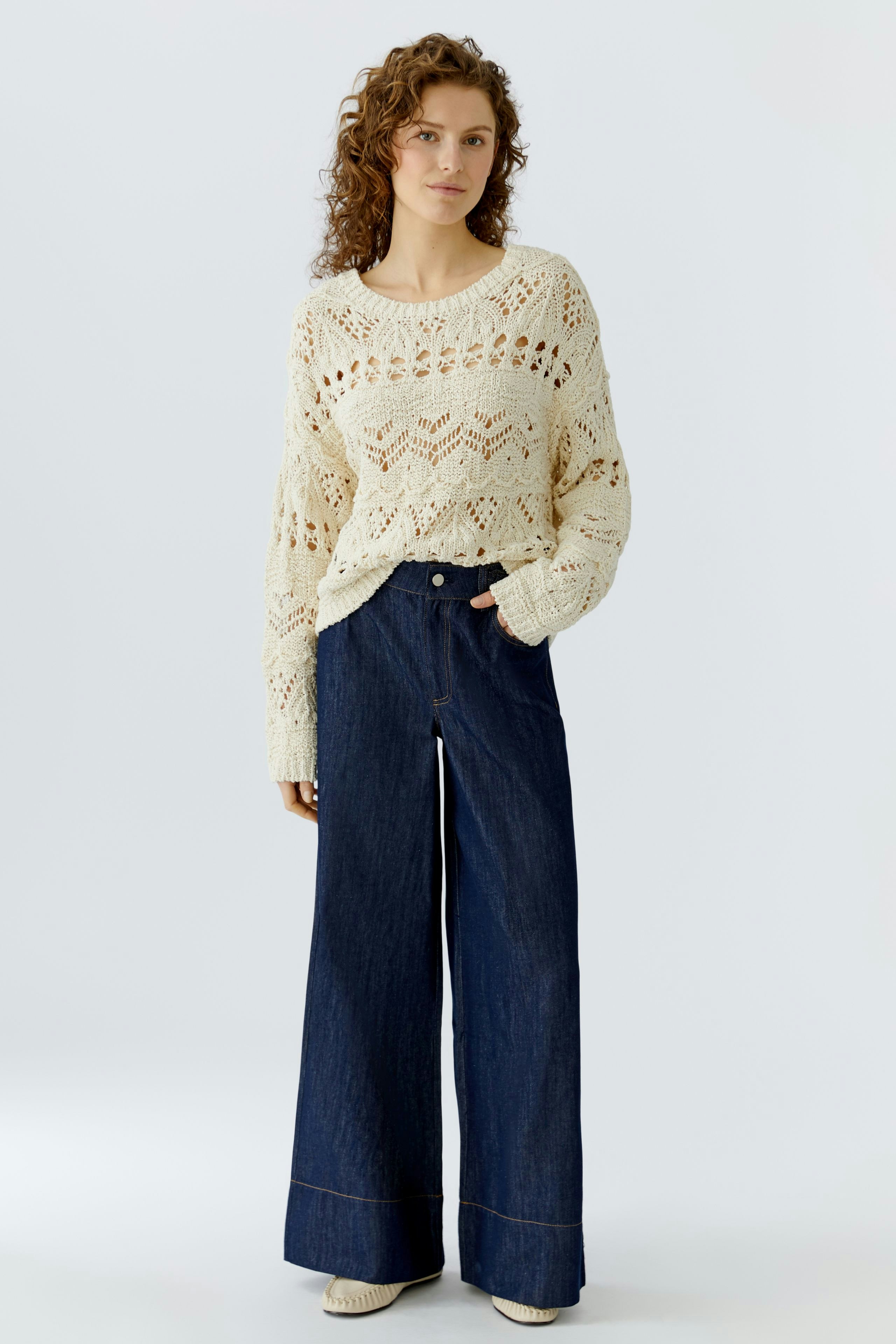 Casual women's pullover: A woman in a cream knit pullover with an open pattern and relaxed fit.