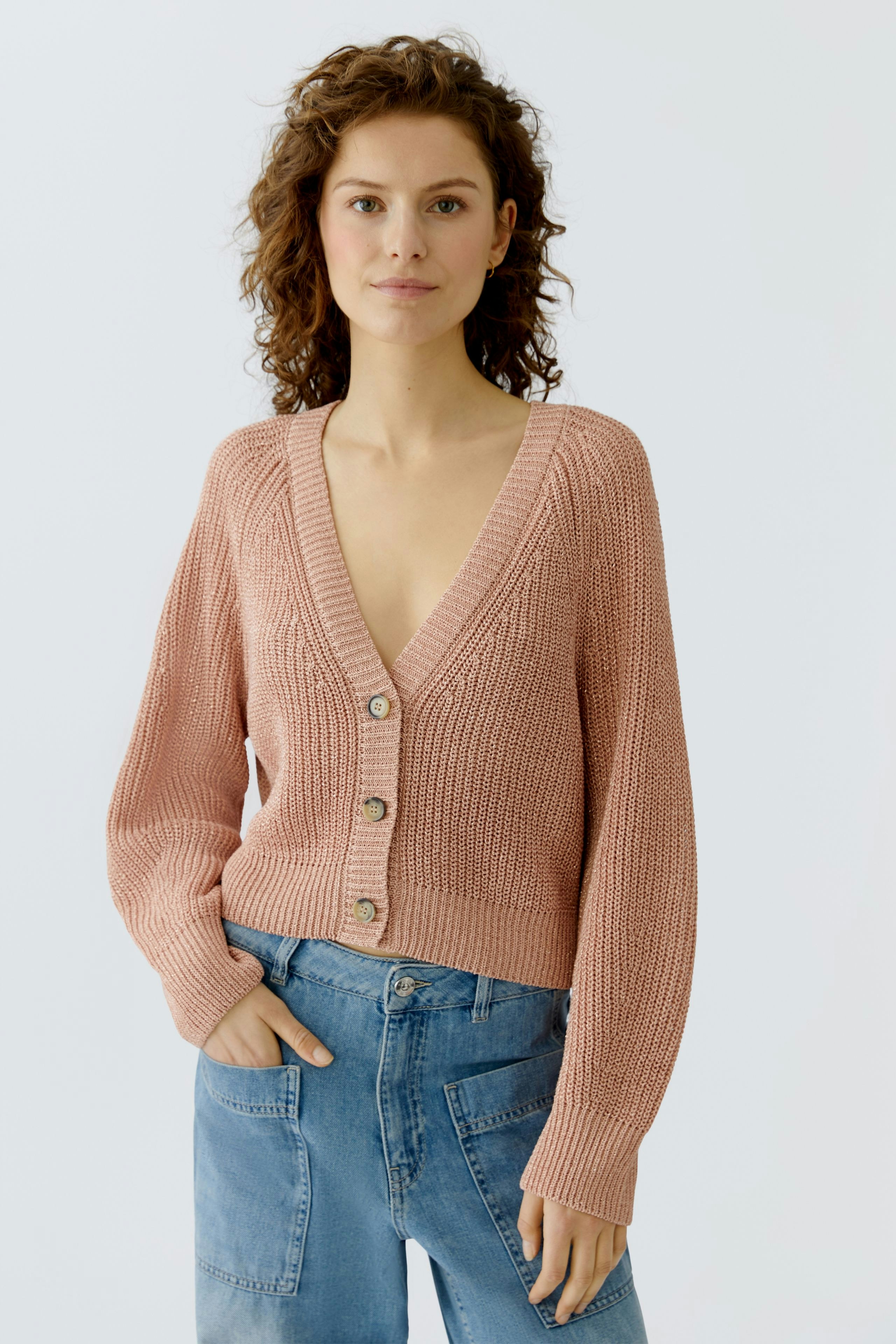 Casual women's cardigan: A woman in a light pink cardigan with buttons and relaxed fit, paired with jeans.