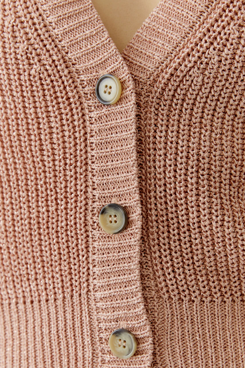 Casual women's cardigan: Close-up of a pink knitted cardigan with buttons, showcasing its textured design.