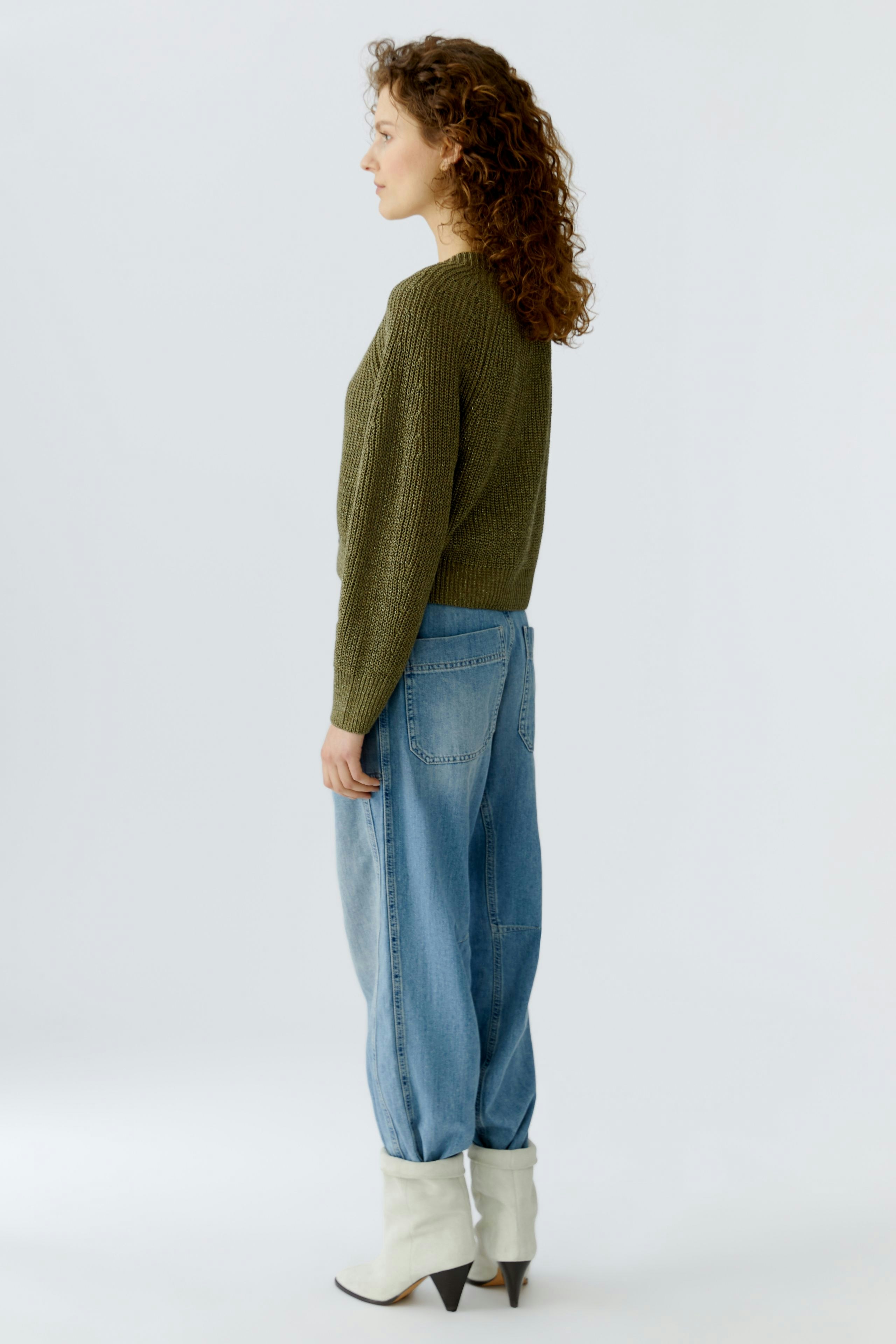 Casual women's cardigan: A woman in a green knitted cardigan paired with relaxed-fit jeans.