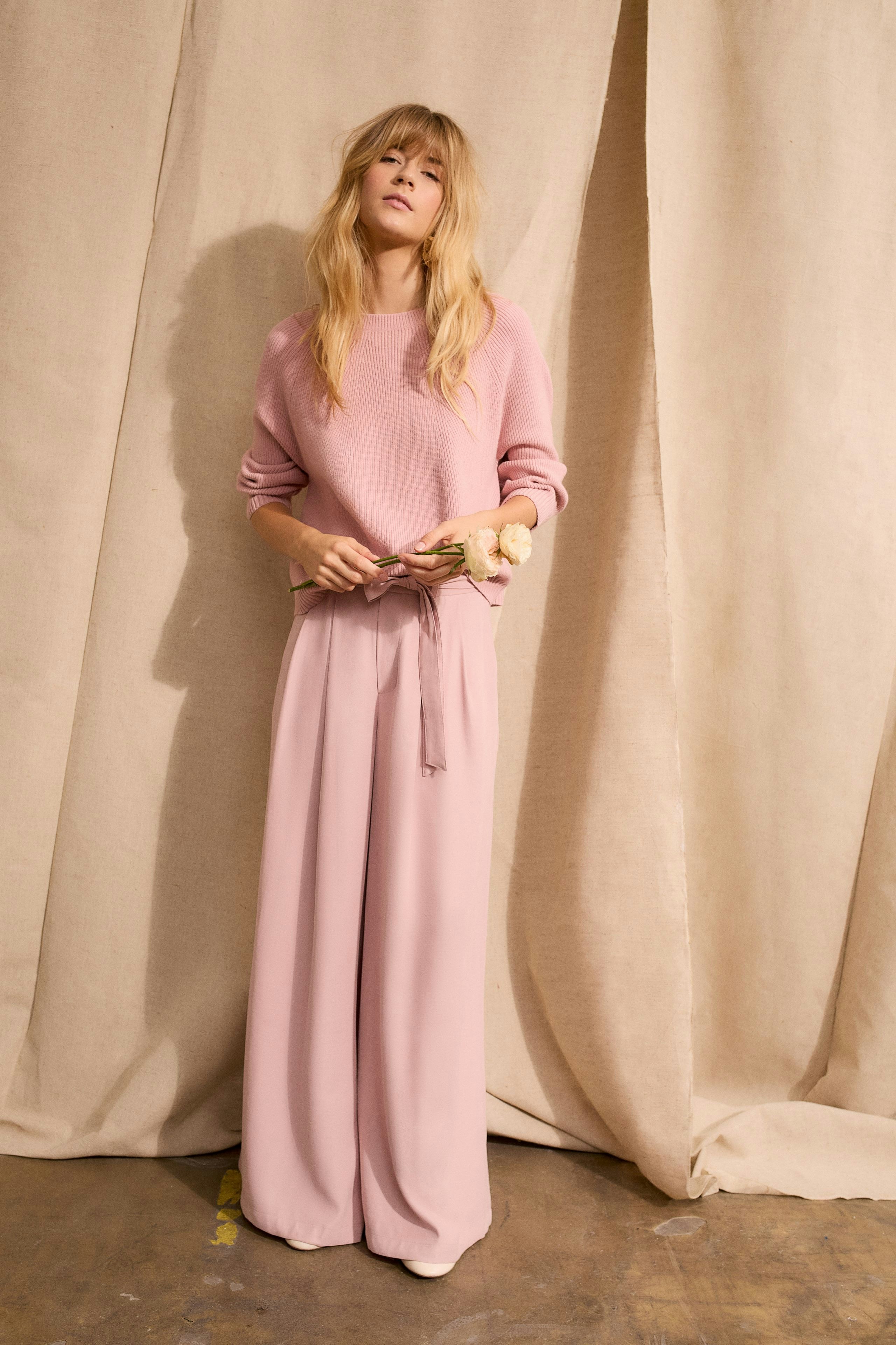 Stylish women's pleated trousers in soft pink, paired with a cozy pullover.