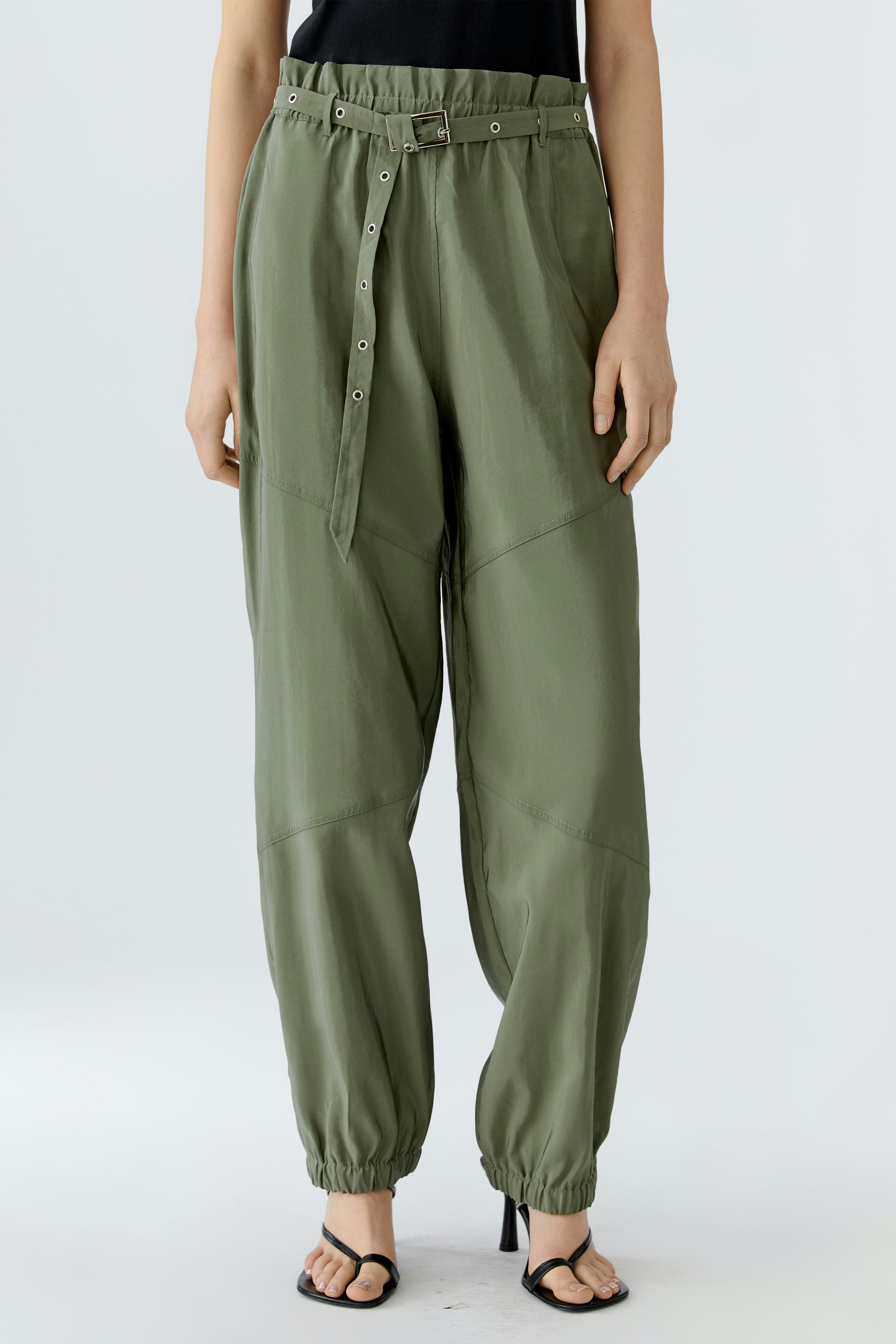 Casual women's pants: A woman in relaxed olive green trousers with a drawstring and button details.