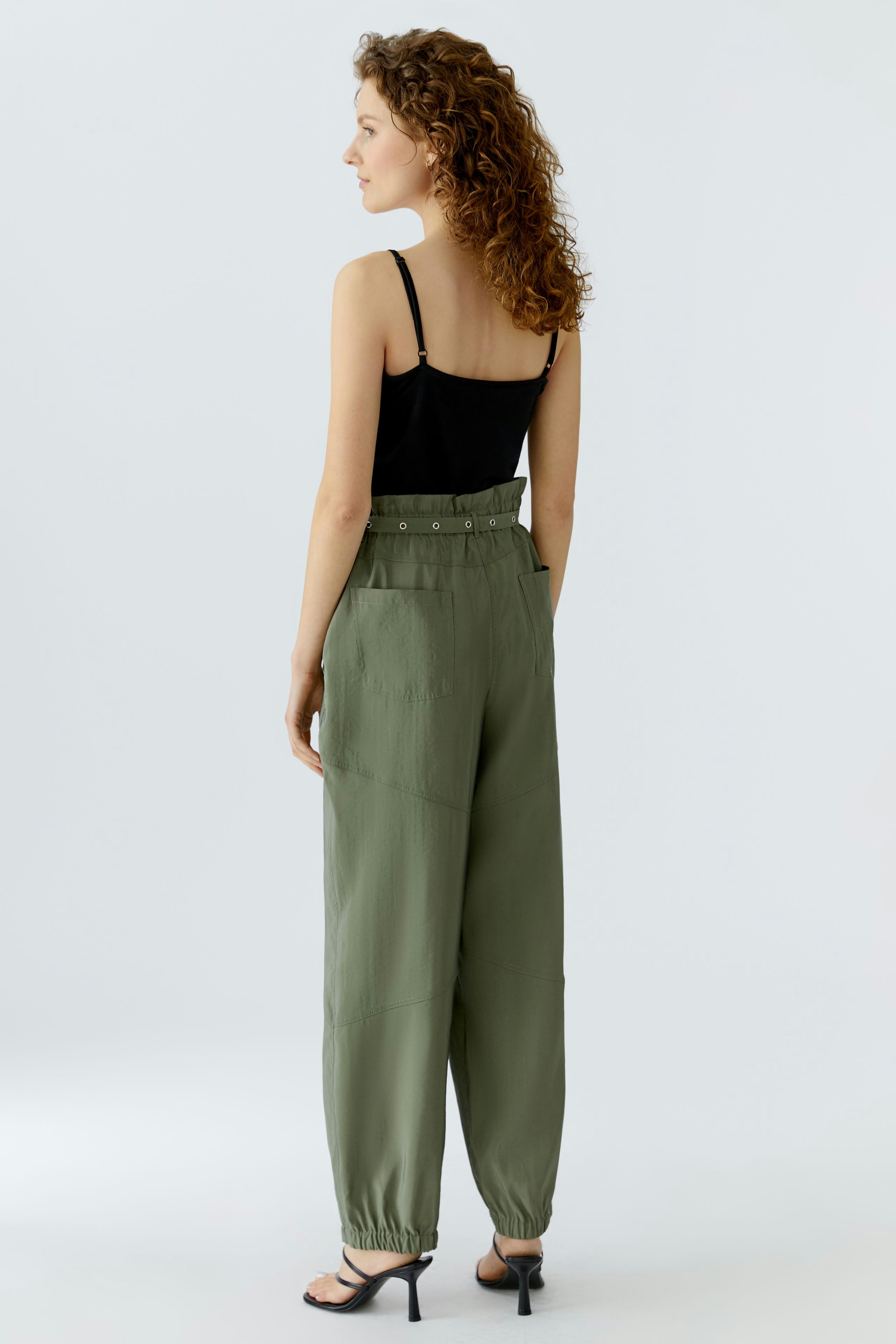 Casual women's pants: A woman in olive green pants with a relaxed fit and side pockets, showcasing comfort.
