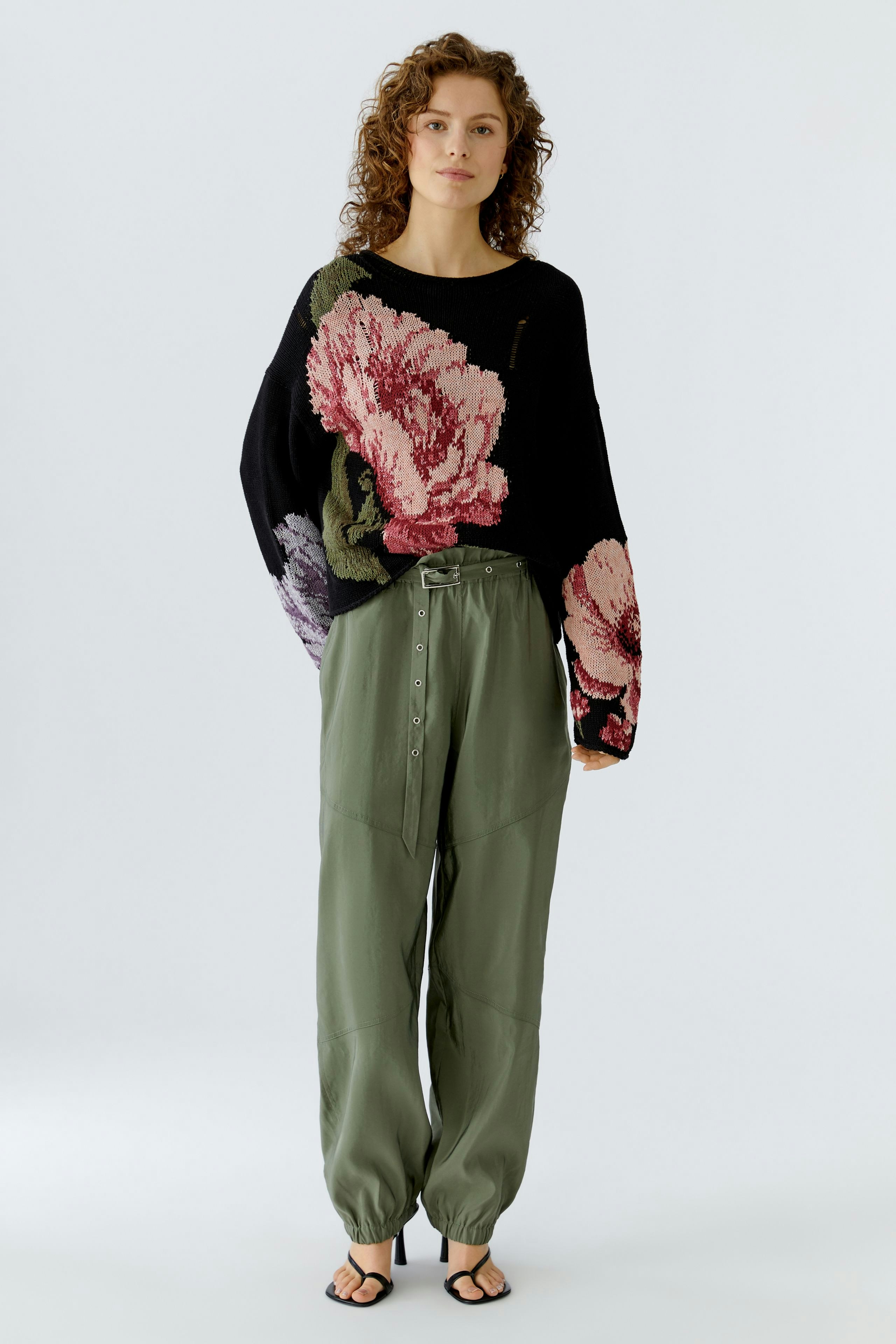 Casual women's pants: A woman in loose-fitting olive green trousers with a floral sweater.