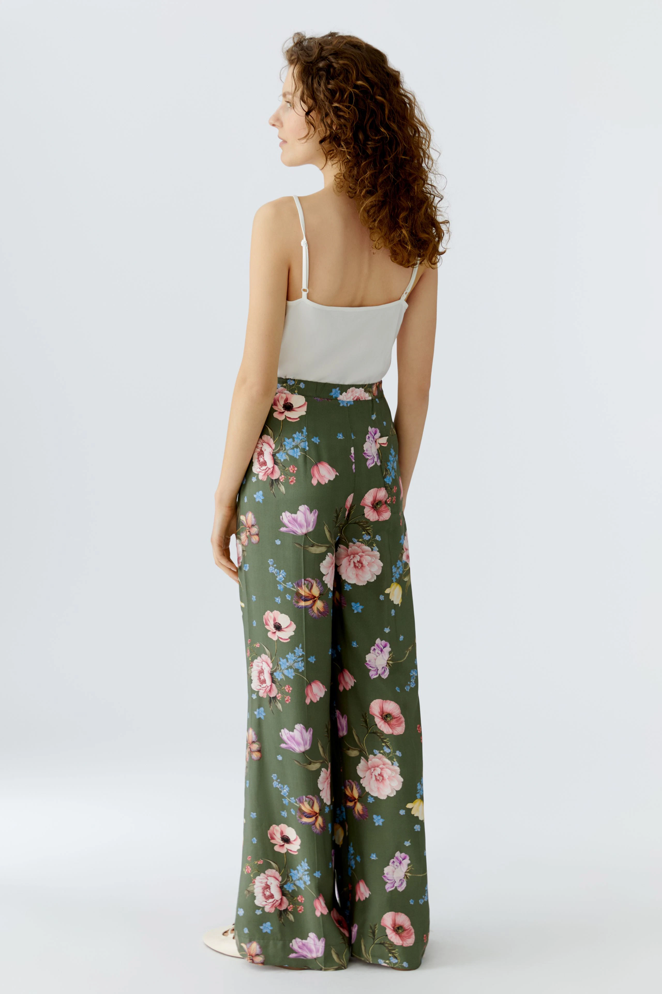 Bequeme Damen-Hose: Frau in floral gemusterter Hose mit weitem Bein und lässigem Top von hinten.