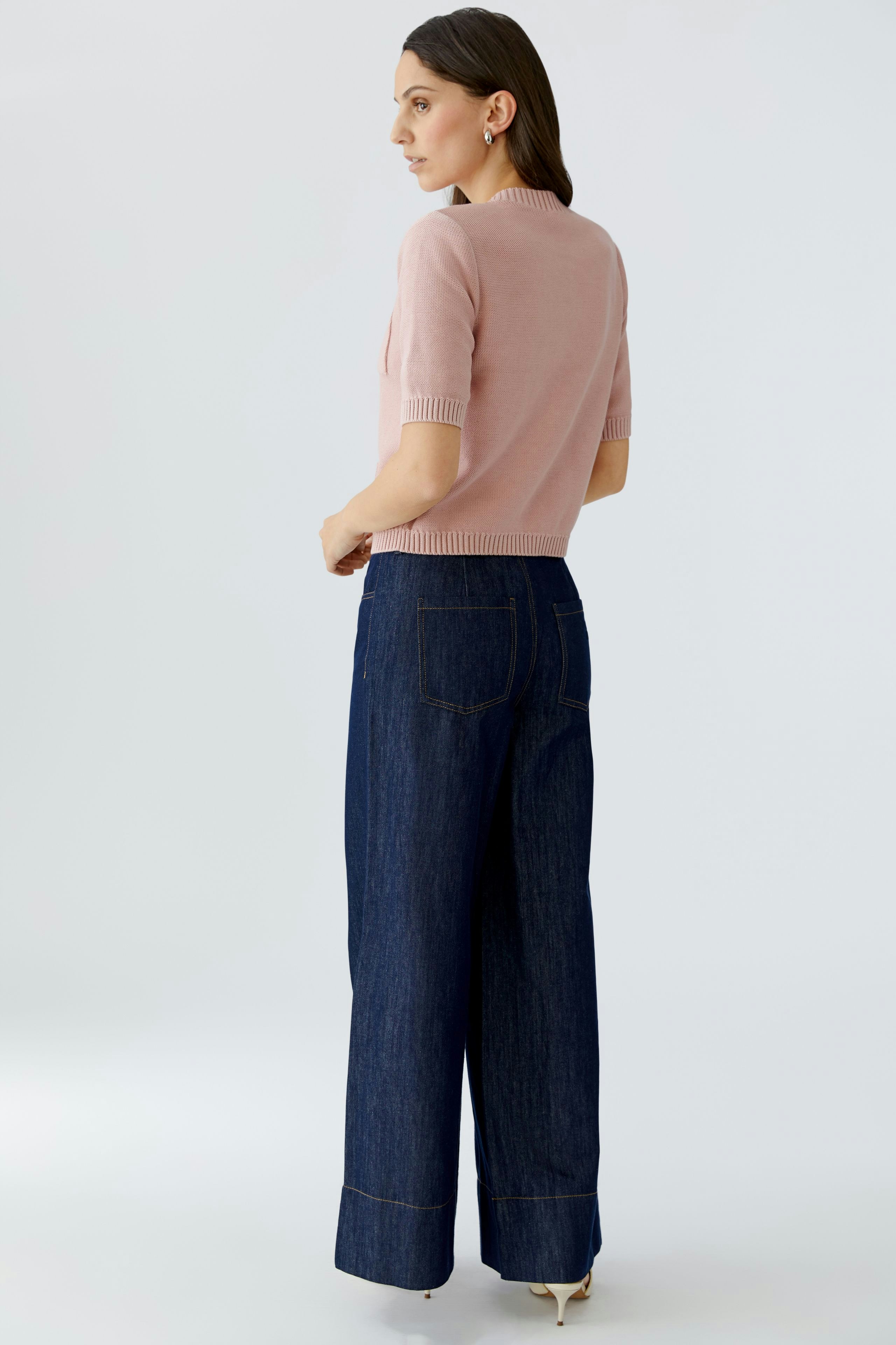 Casual women's pullover: A woman in a pink short-sleeve pullover paired with wide-leg jeans.