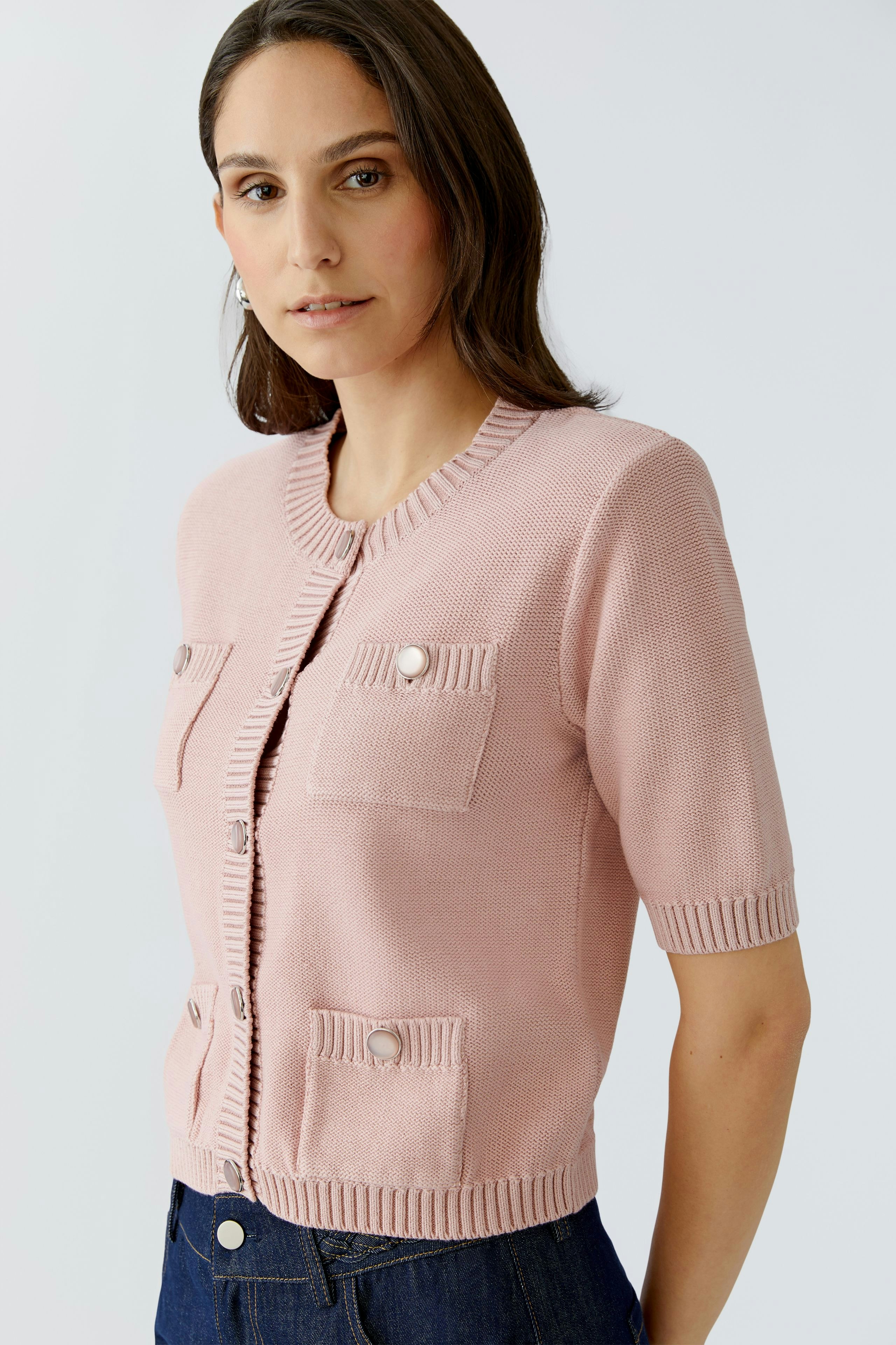 Casual women's cardigan: A woman in a light pink cardigan with pockets and short sleeves.