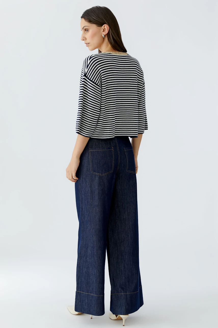 Damen-Strickjacke: Frau mit gestreiftem Oberteil und weiten Jeans von hinten.