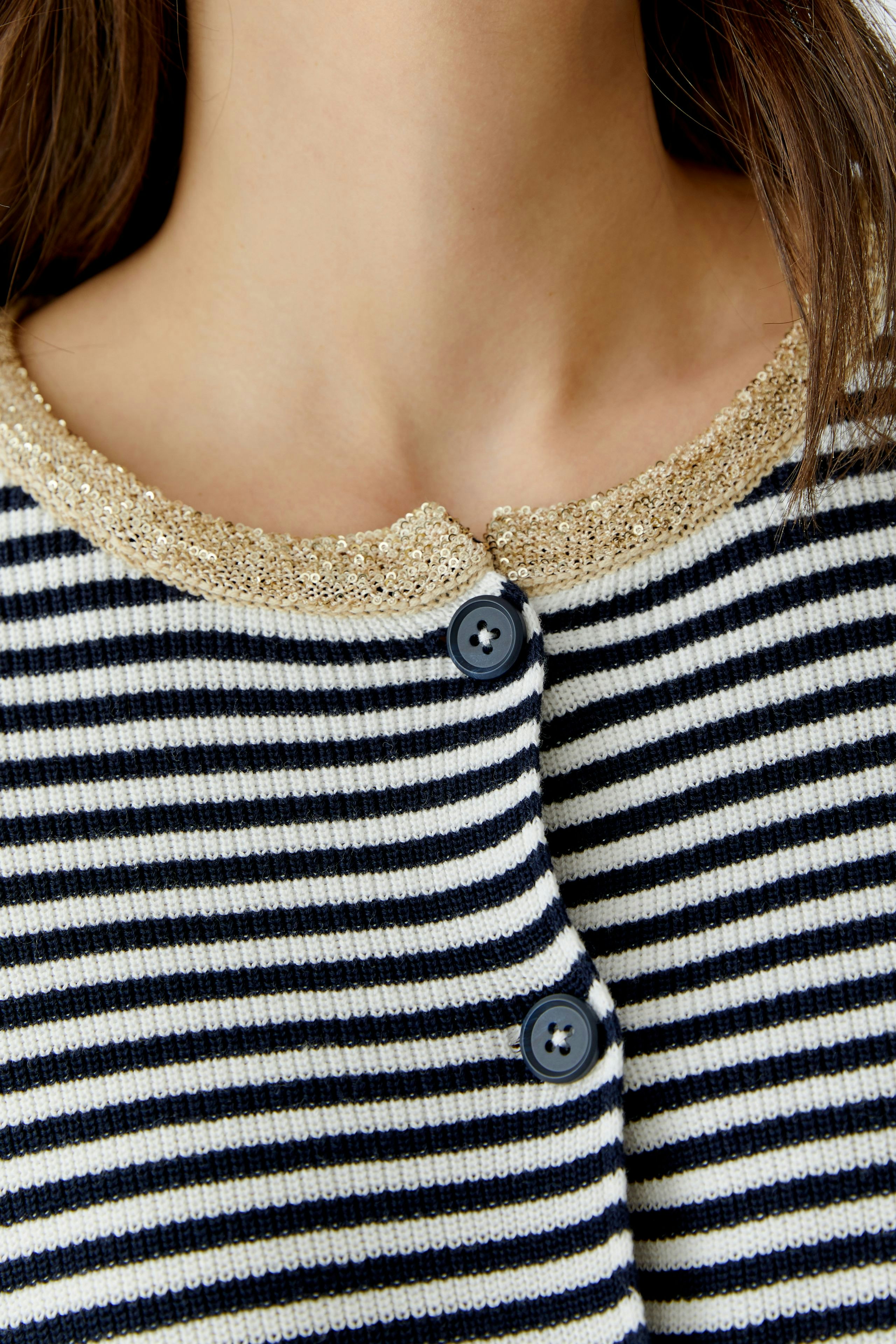 Casual women's cardigan: Close-up of a woman wearing a striped cardigan with a shiny collar.