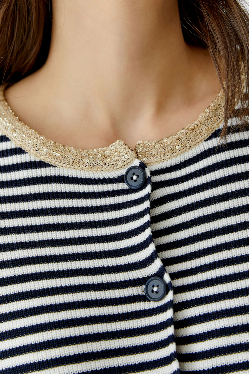 Damen-Strickjacke: Frau mit gestreifter Jacke und glitzerndem Kragen, lässiger Look.