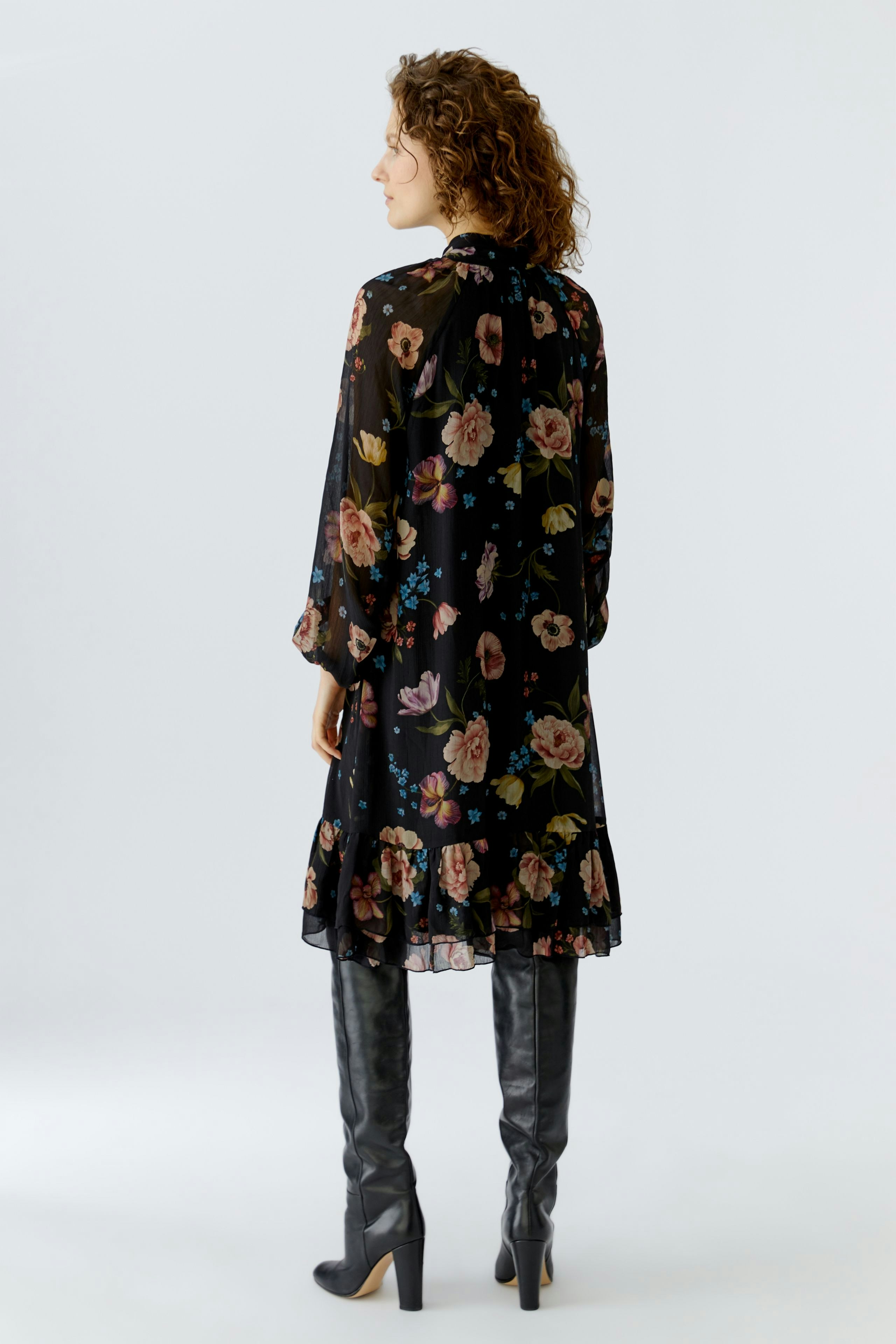 A-line dress: Woman in a floral black dress with long sleeves and knee-high boots.