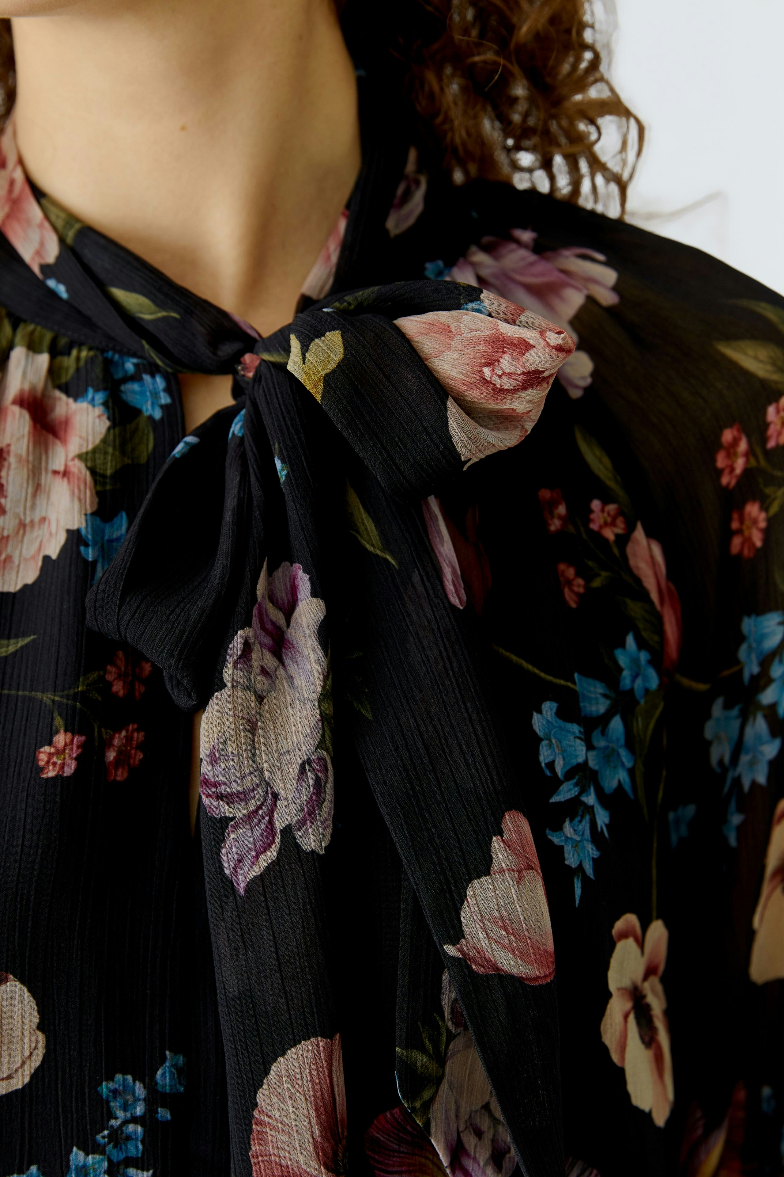 A-line dress: Woman in a floral black dress with a bow tie detail, showcasing vibrant colors.