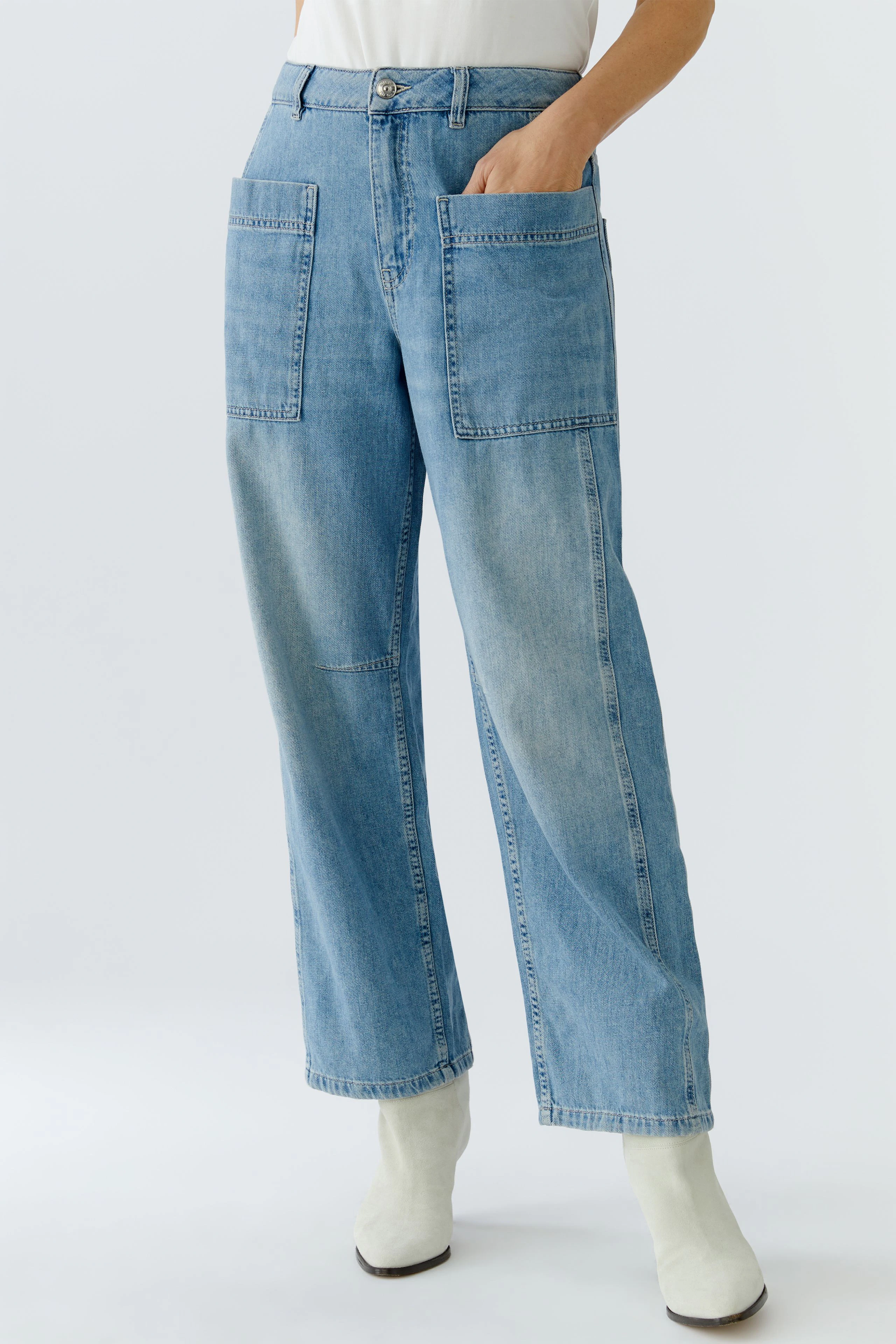 Bequeme Jeans Barrel: Frau trägt lässige, hellblaue Jeans mit großen Taschen und weitem Schnitt.