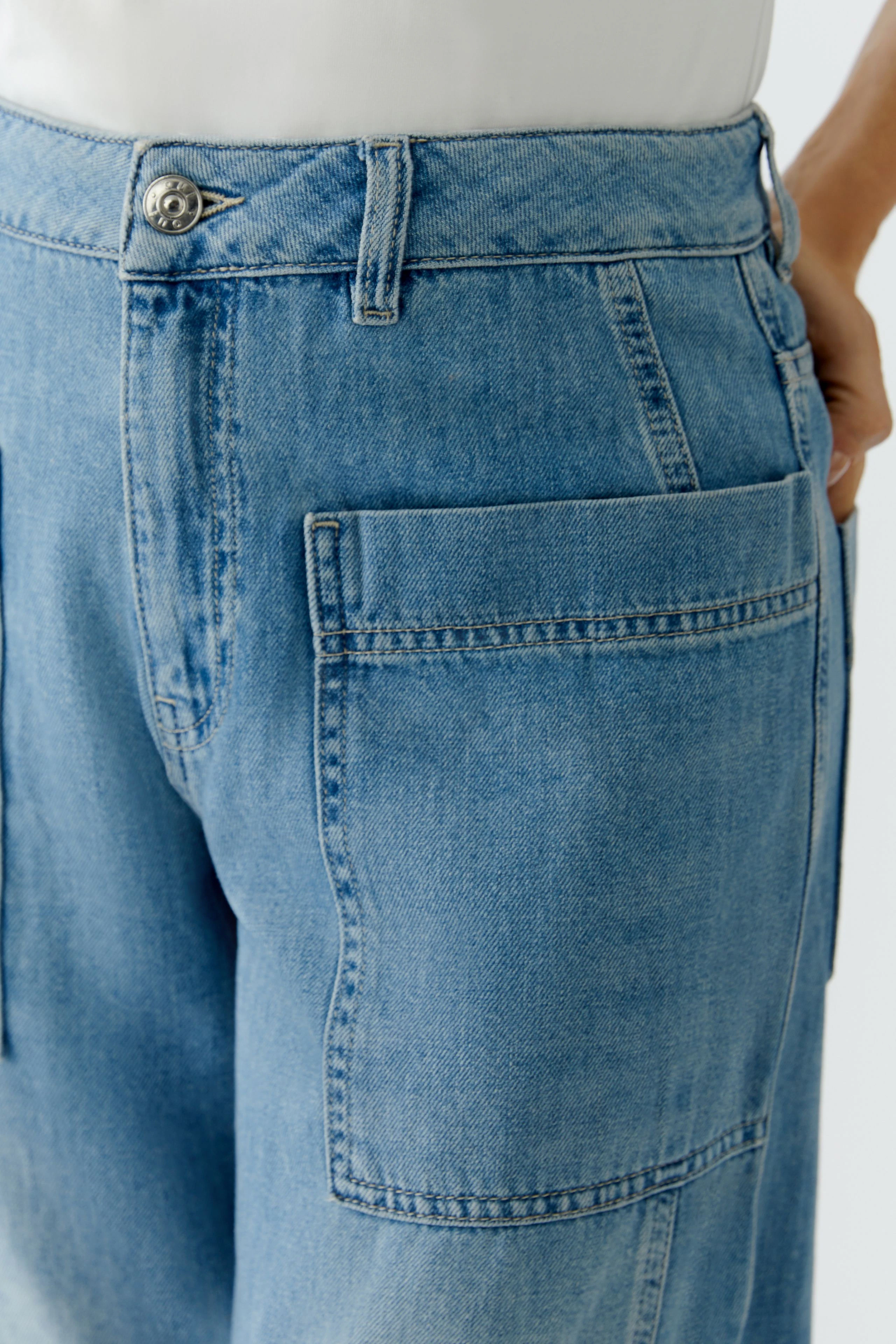 Bequeme Jeans Barrel: Frau trägt lässige, hellblaue Jeans mit praktischen Taschen und lockerer Passform.