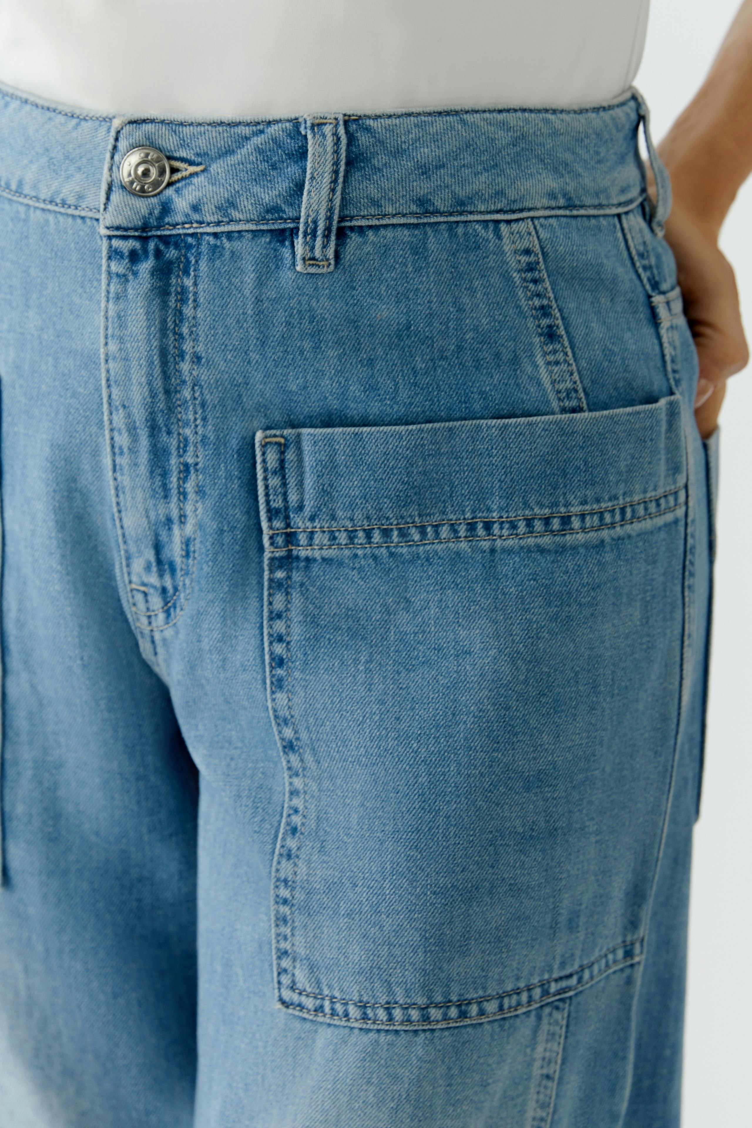 Casual women's jeans barrel: Close-up of a woman wearing light blue jeans with a relaxed fit and pockets.