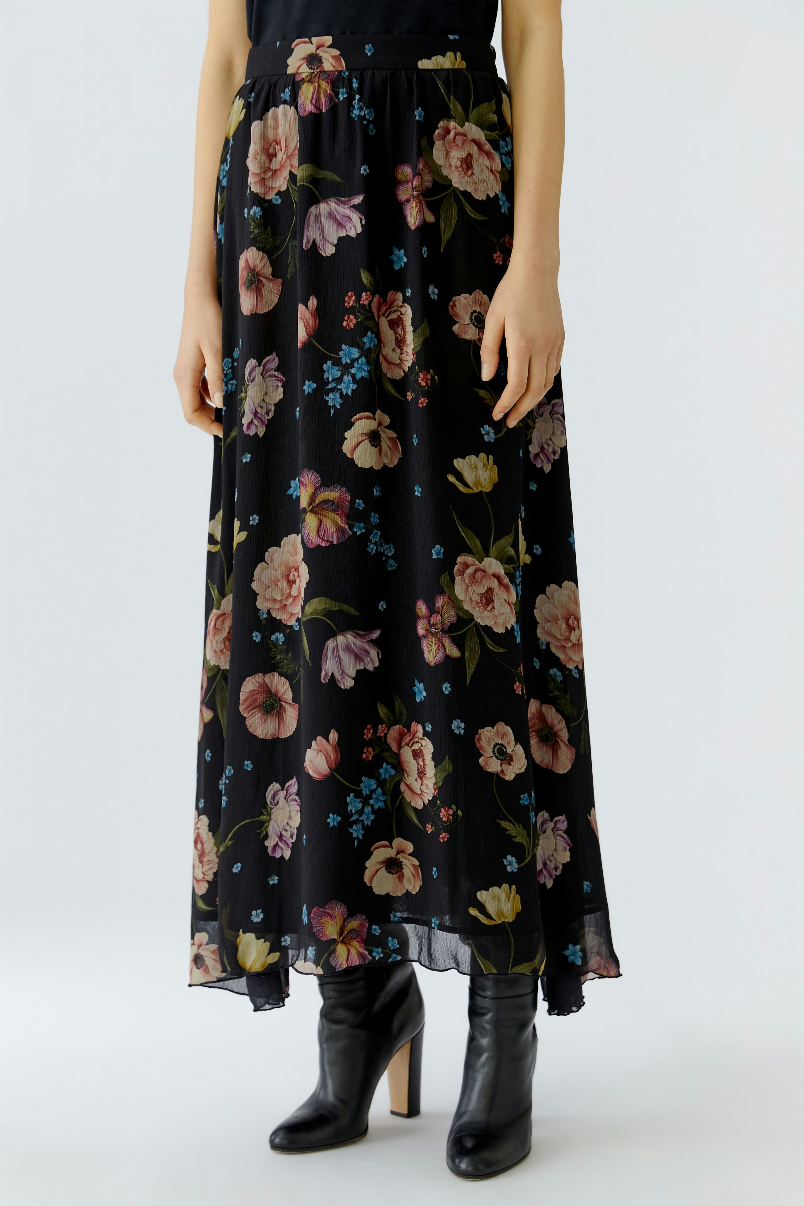Floral maxi skirt: Woman in a black skirt with colorful flowers, paired with stylish ankle boots.