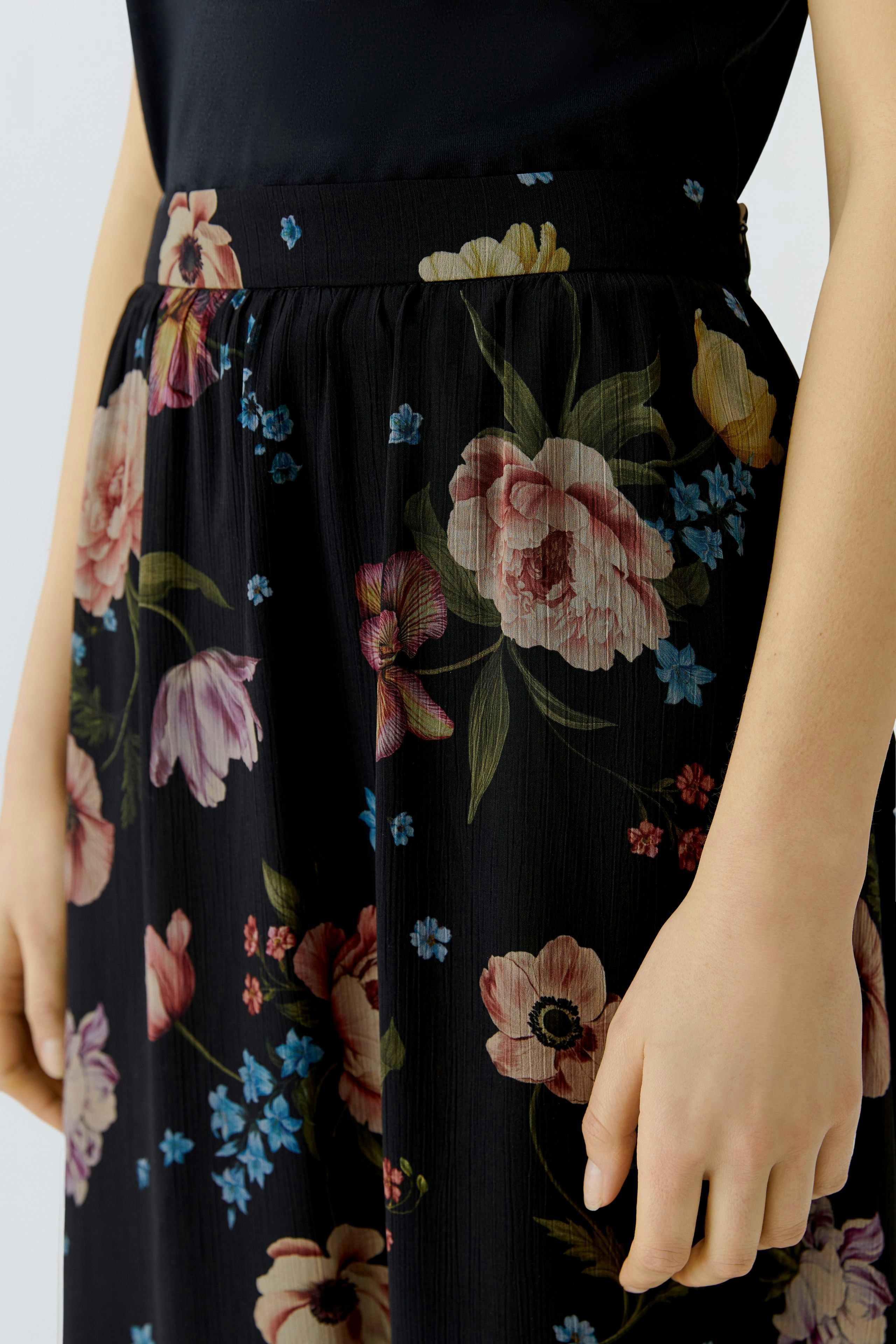 Floral maxi skirt: Woman wearing a black skirt with colorful flowers, perfect for casual outings.