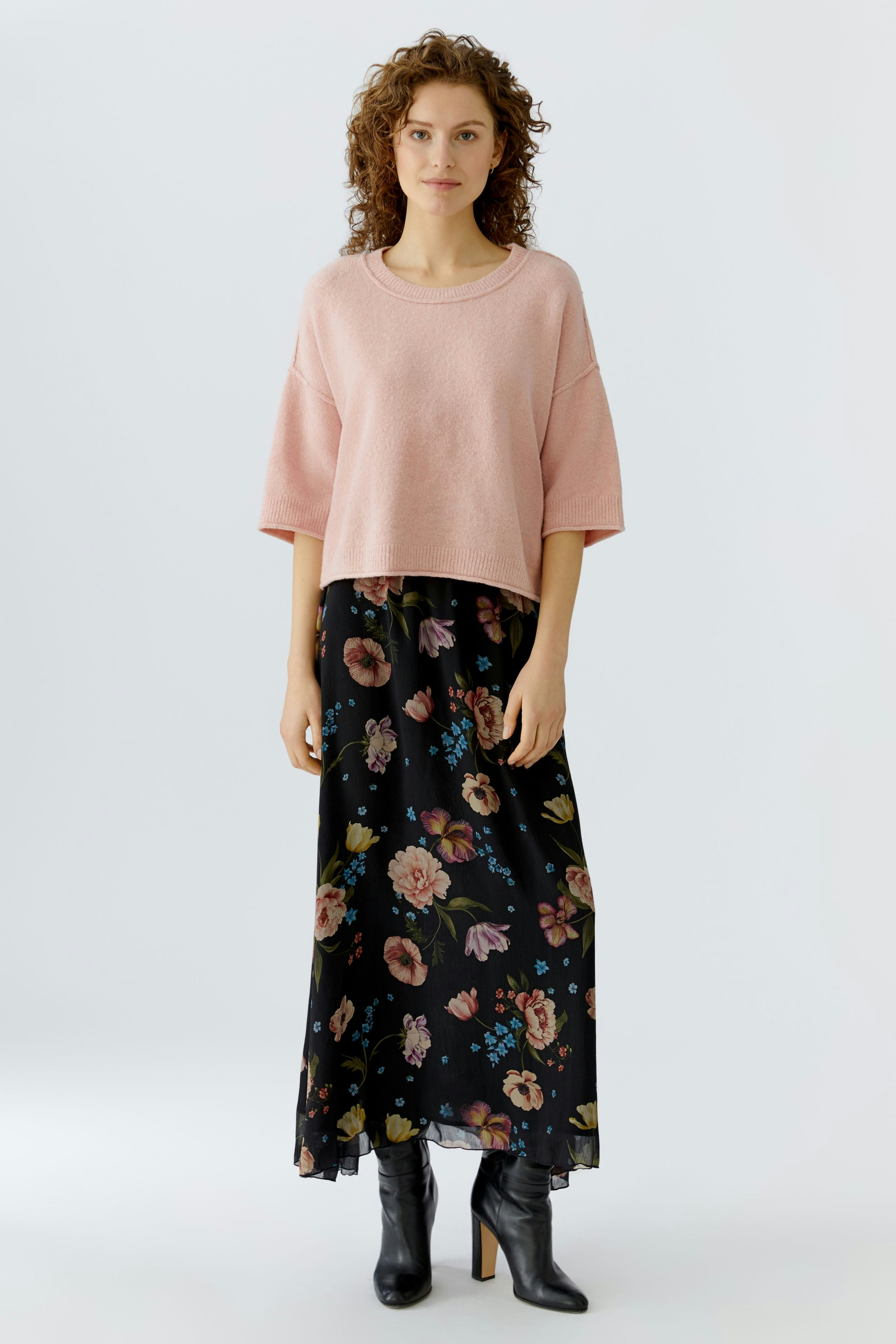 Casual maxi skirt: Woman in a floral black maxi skirt paired with a pink pullover.