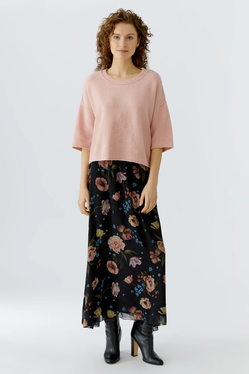 Casual maxi skirt: Woman in a floral black maxi skirt paired with a pink pullover.
