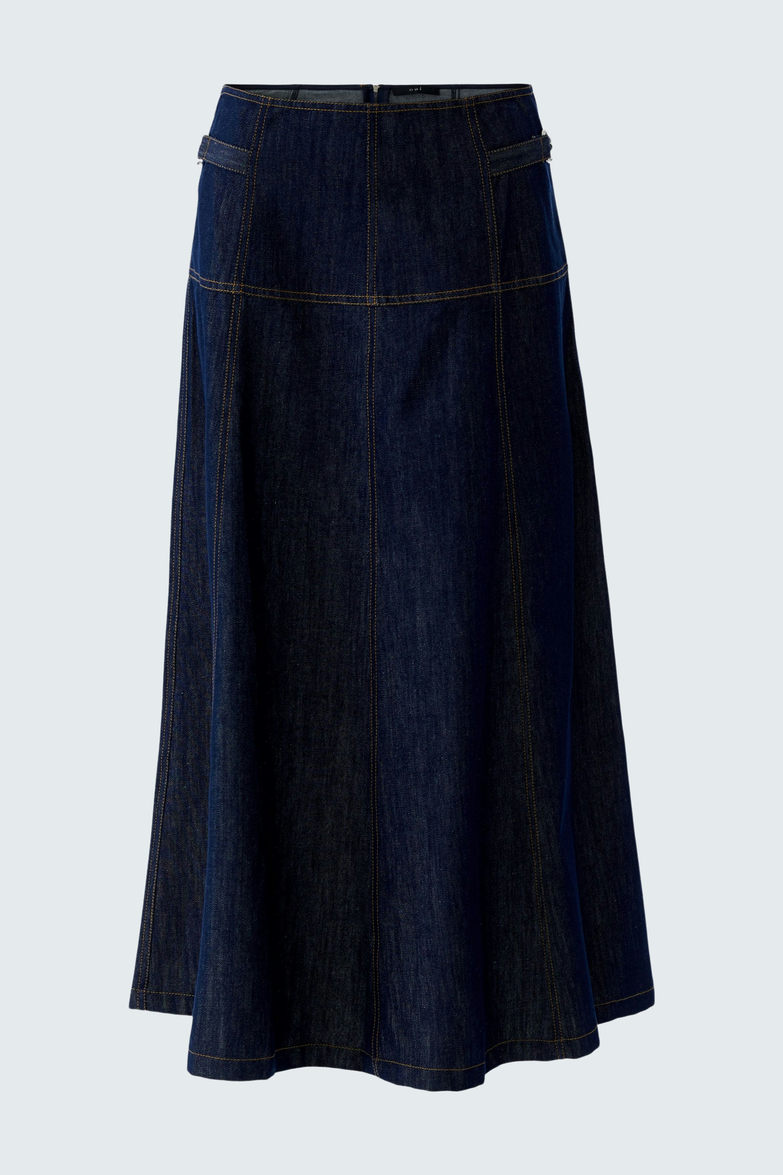Denim A-line skirt: A woman in a dark blue A-line skirt with visible stitching, showcasing a casual style.