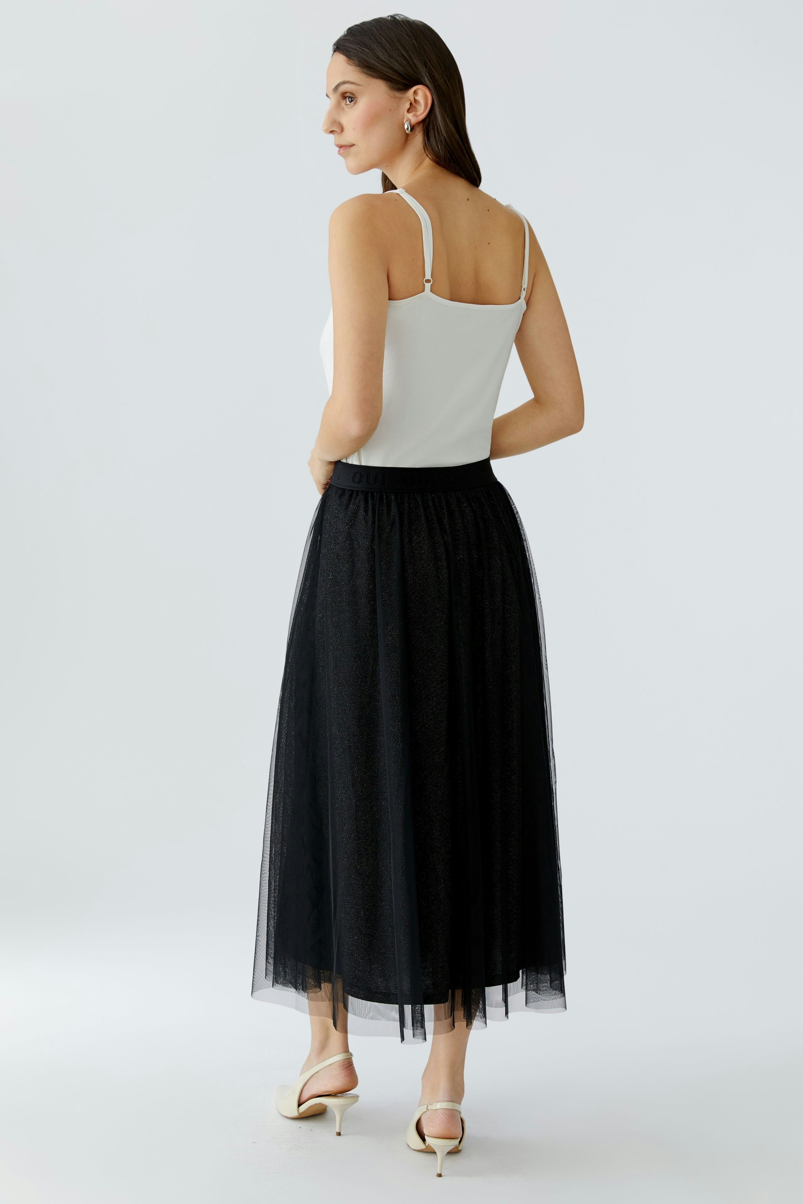 A-line skirt: Woman in a black tulle skirt with a fitted waistband, showcasing a casual style.