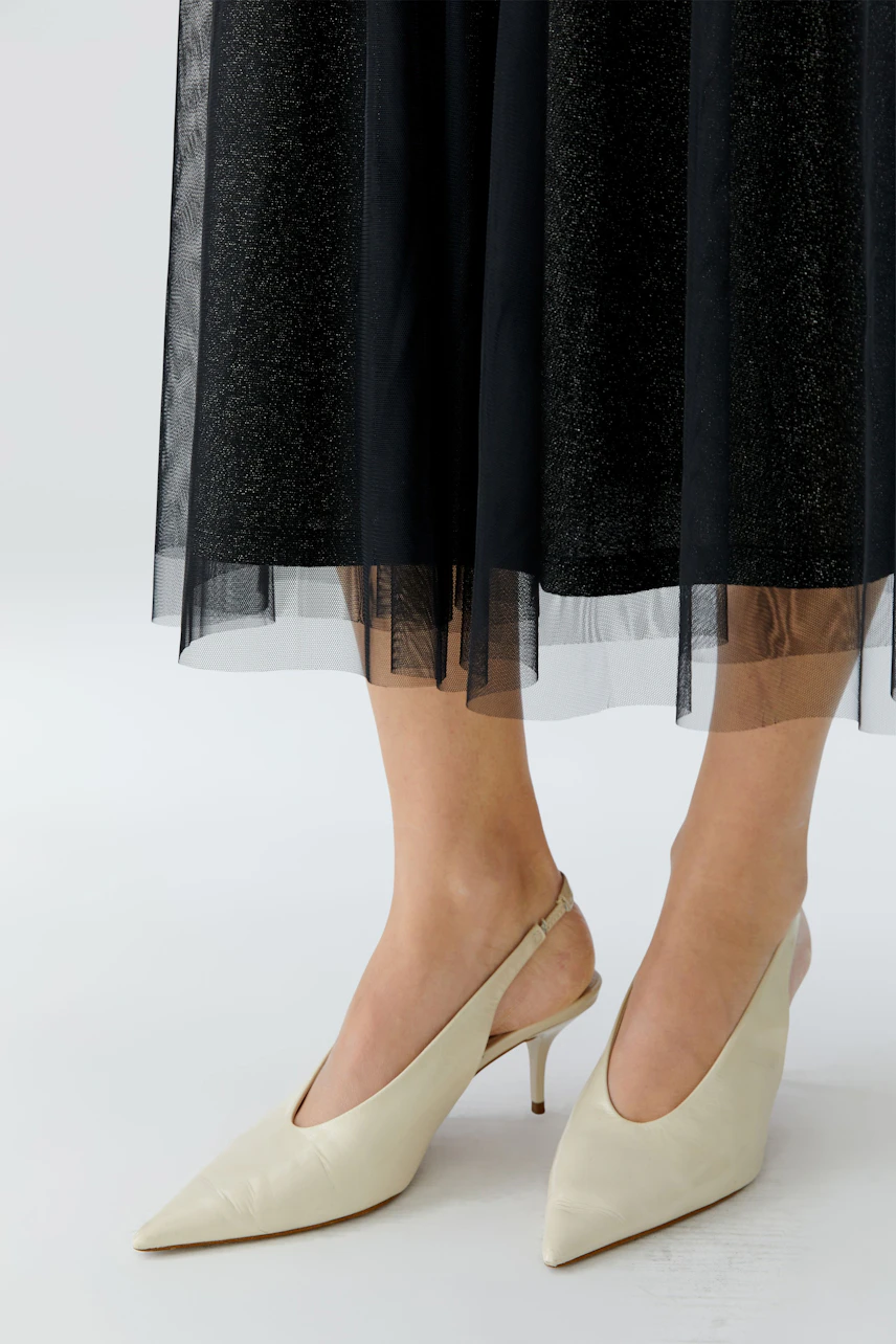 A-Linien-Rock: Frau trägt einen schwarzen, schwingenden A-Linien-Rock mit transparentem Unterteil.