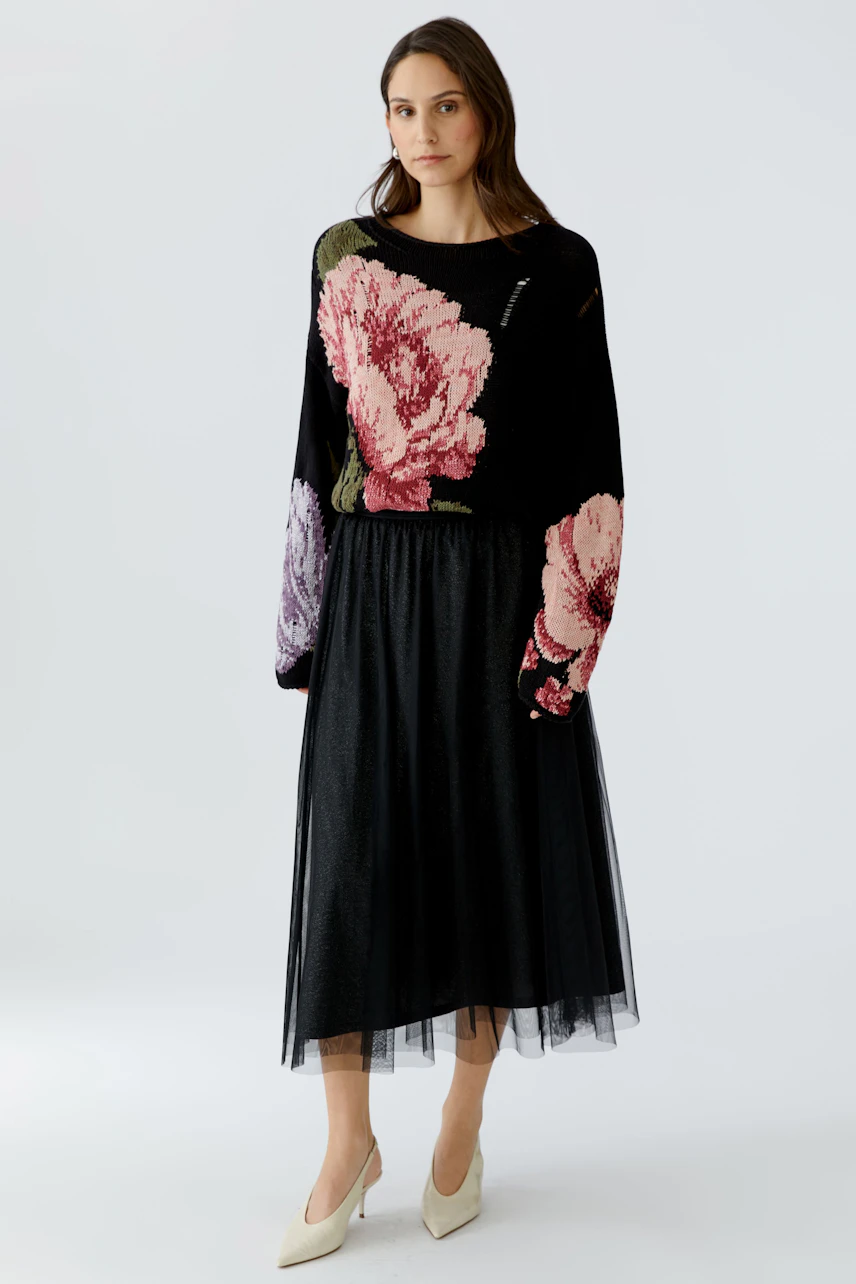 Damen A-Linien-Rock: Frau trägt einen schwarzen Rock mit floralen Details und lässigem Oberteil.