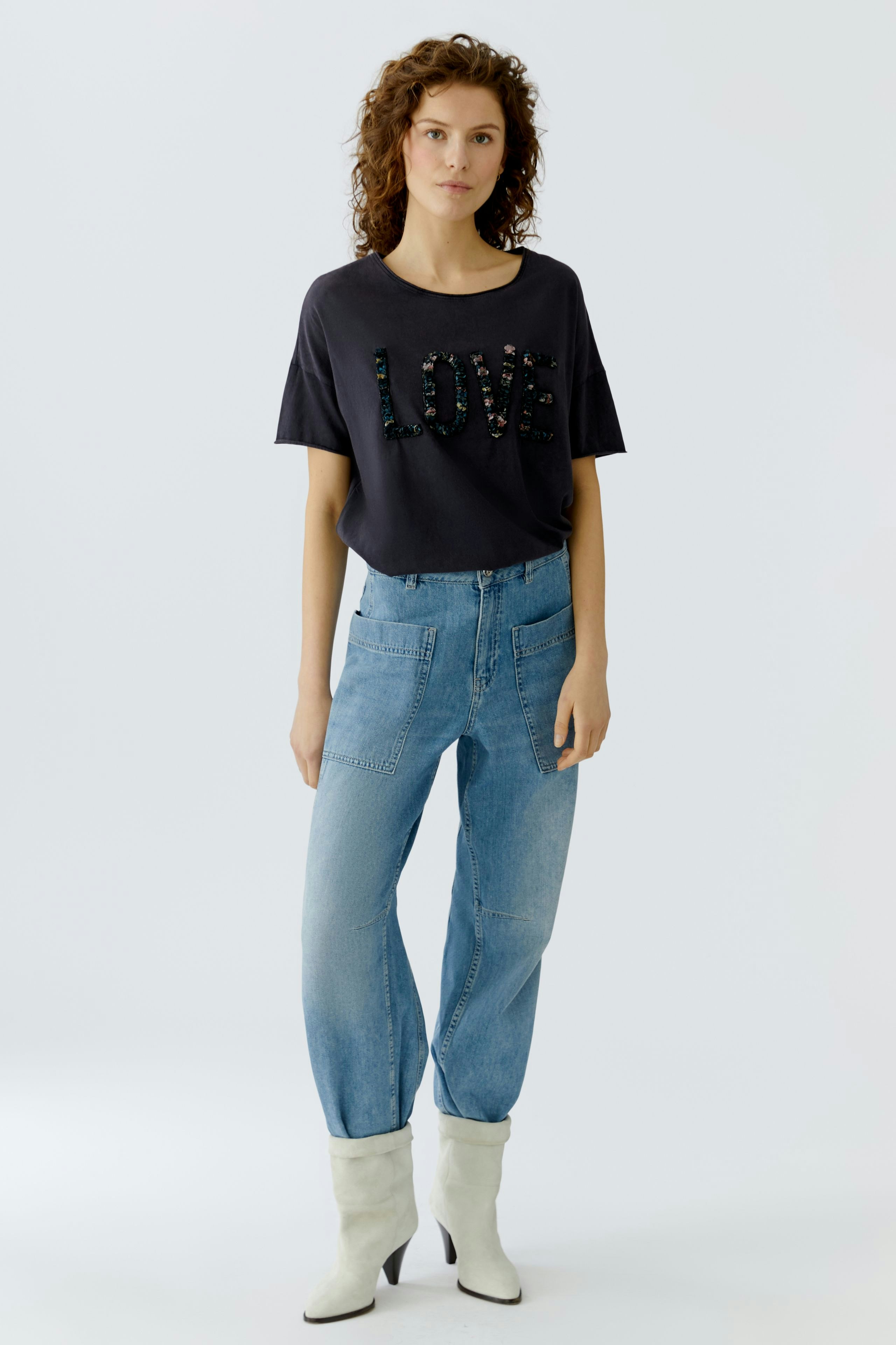 Casual women's T-shirt: Young woman in a navy tee with 'LOVE' design, paired with light blue jeans.