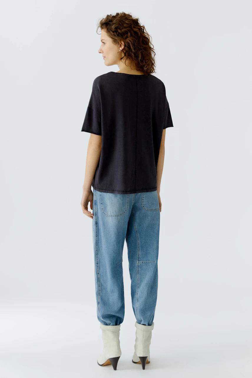 Casual women's T-shirt: A woman in a black T-shirt paired with relaxed blue jeans, showcasing a laid-back style.