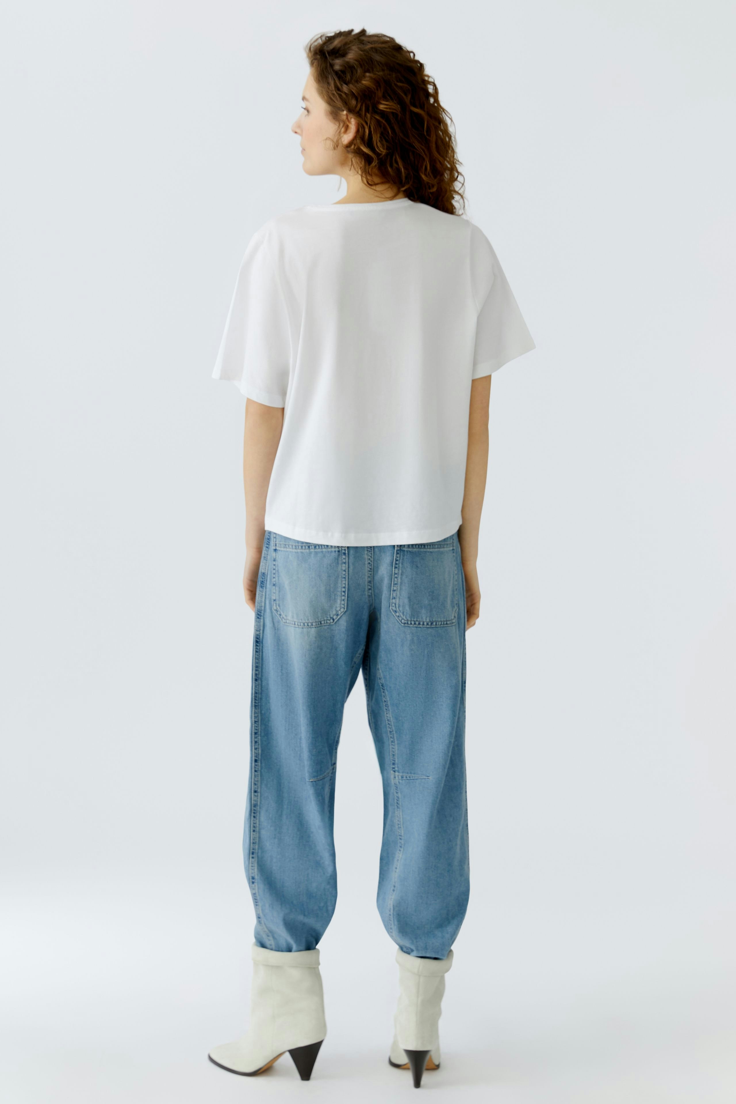 Casual women's T-shirt: A woman in a white T-shirt paired with relaxed blue jeans.