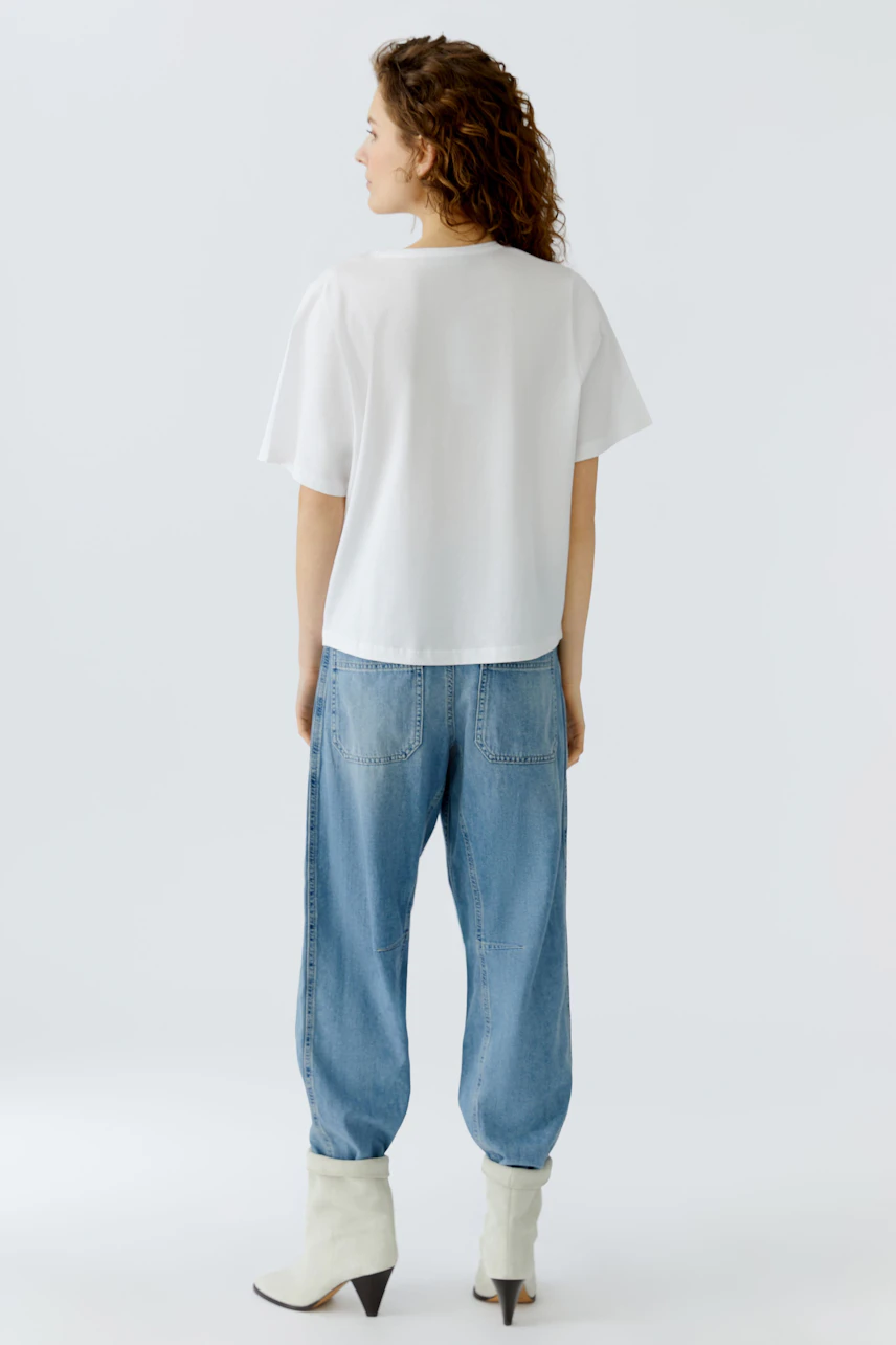 Casual women's T-shirt: A woman in a white T-shirt paired with relaxed blue jeans.