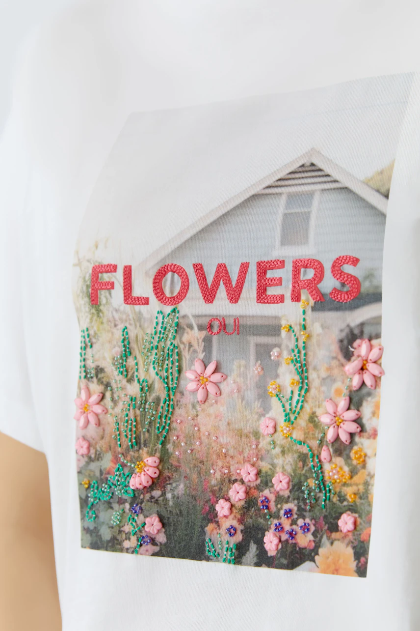 Casual women's T-shirt featuring a floral print and colorful embellishments.