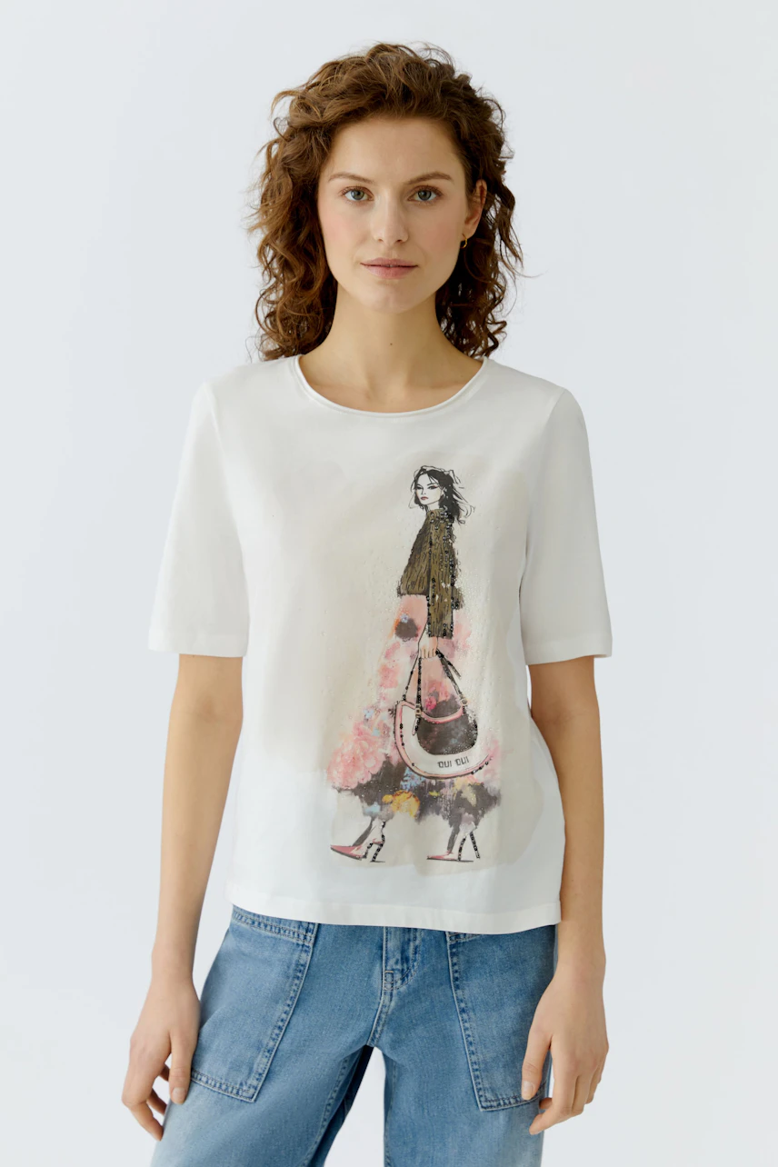 Casual women's T-shirt: Woman in a white tee with a colorful fashion illustration, paired with denim.