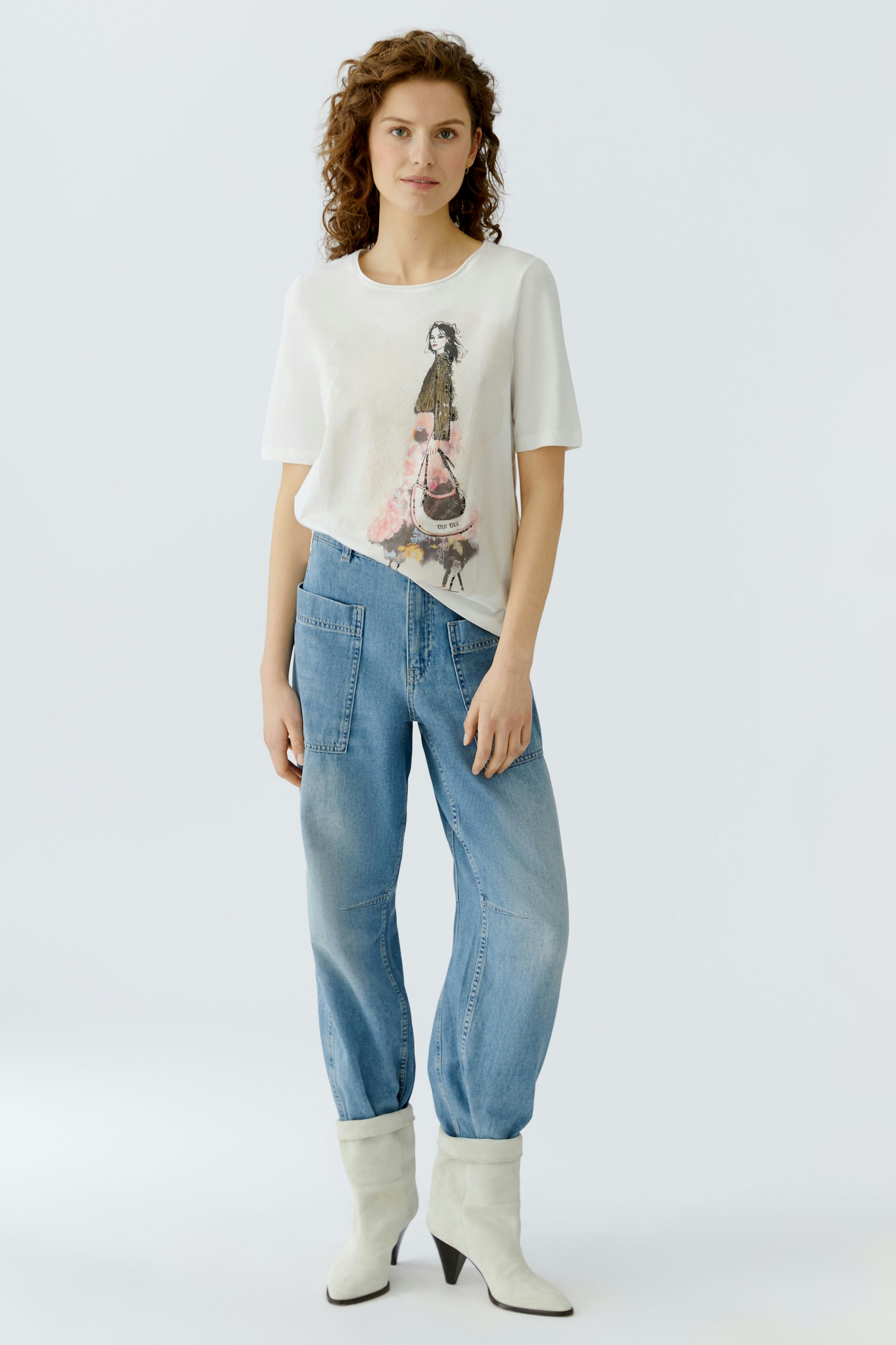 Casual women's T-shirt: Woman in a white tee with a playful graphic design, paired with relaxed jeans.