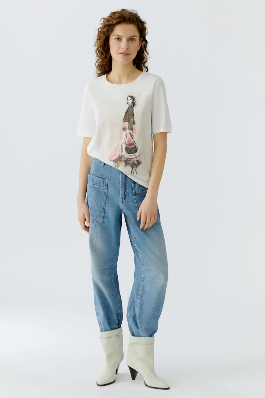 Casual women's T-shirt: Woman in a white tee with a playful graphic design, paired with relaxed jeans.