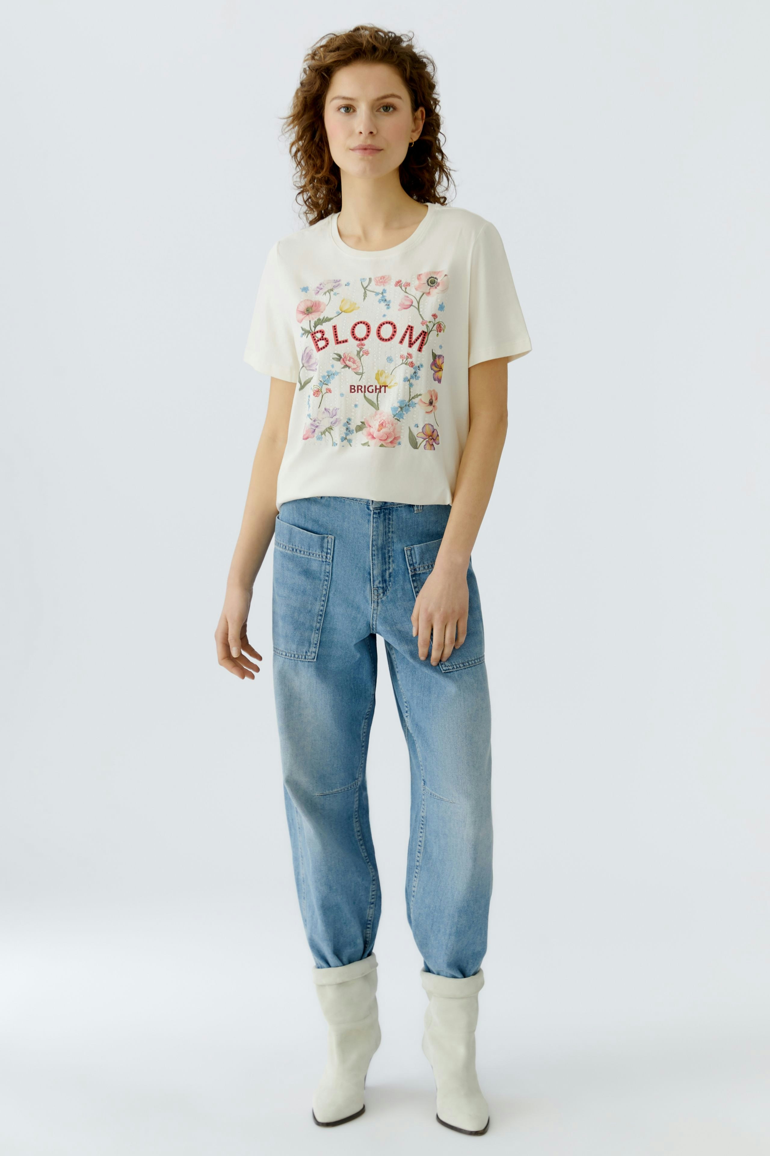 Casual women's T-shirt: Young woman in a floral print tee with relaxed jeans, exuding a fresh vibe.