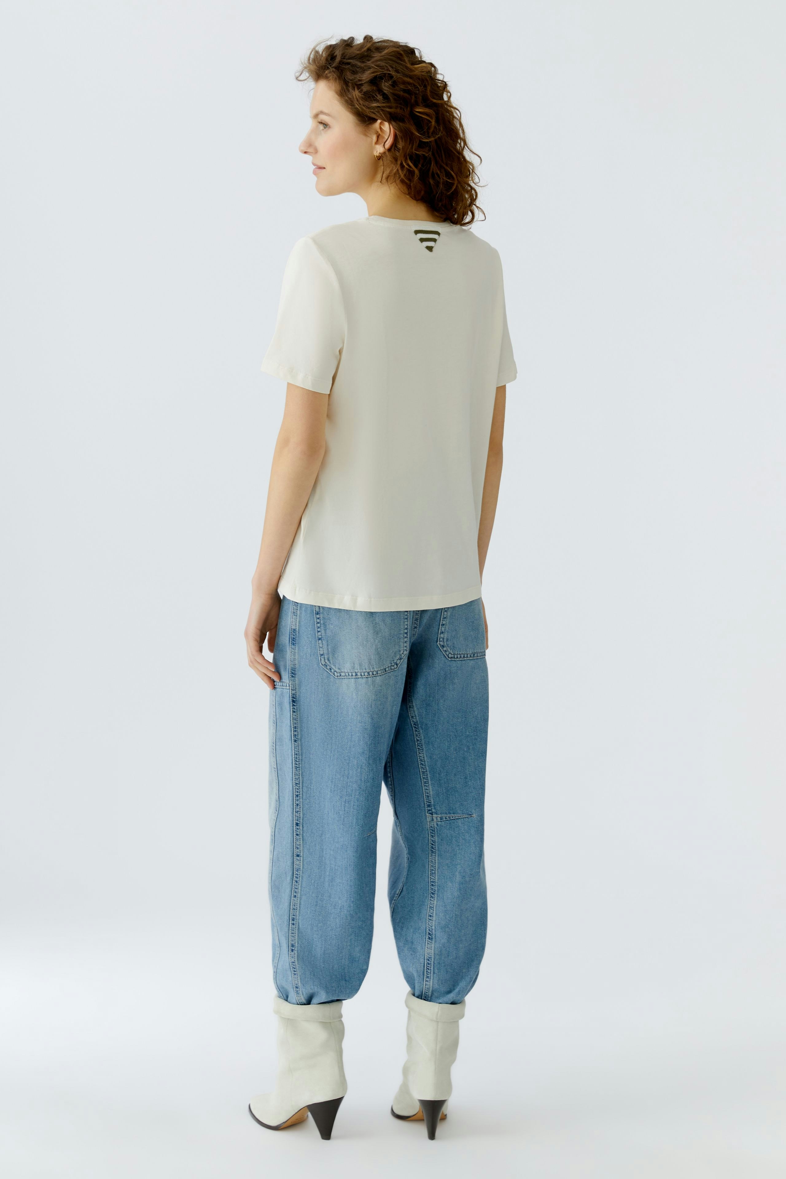 Casual women's T-shirt: A woman in a light top and relaxed jeans, showcasing a simple and modern style.