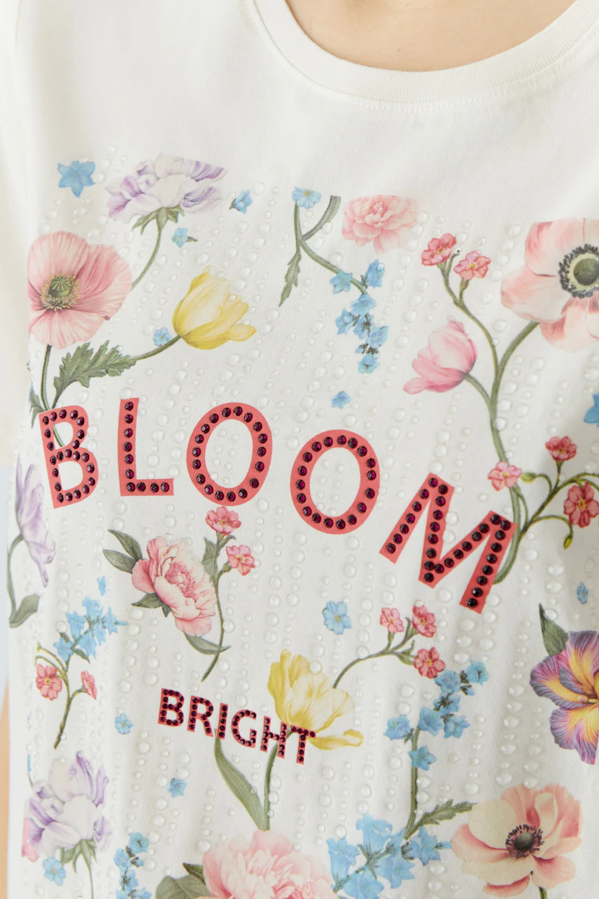Casual women's T-shirt: Close-up of a woman wearing a white tee with floral print and 'BLOOM BRIGHT' text.