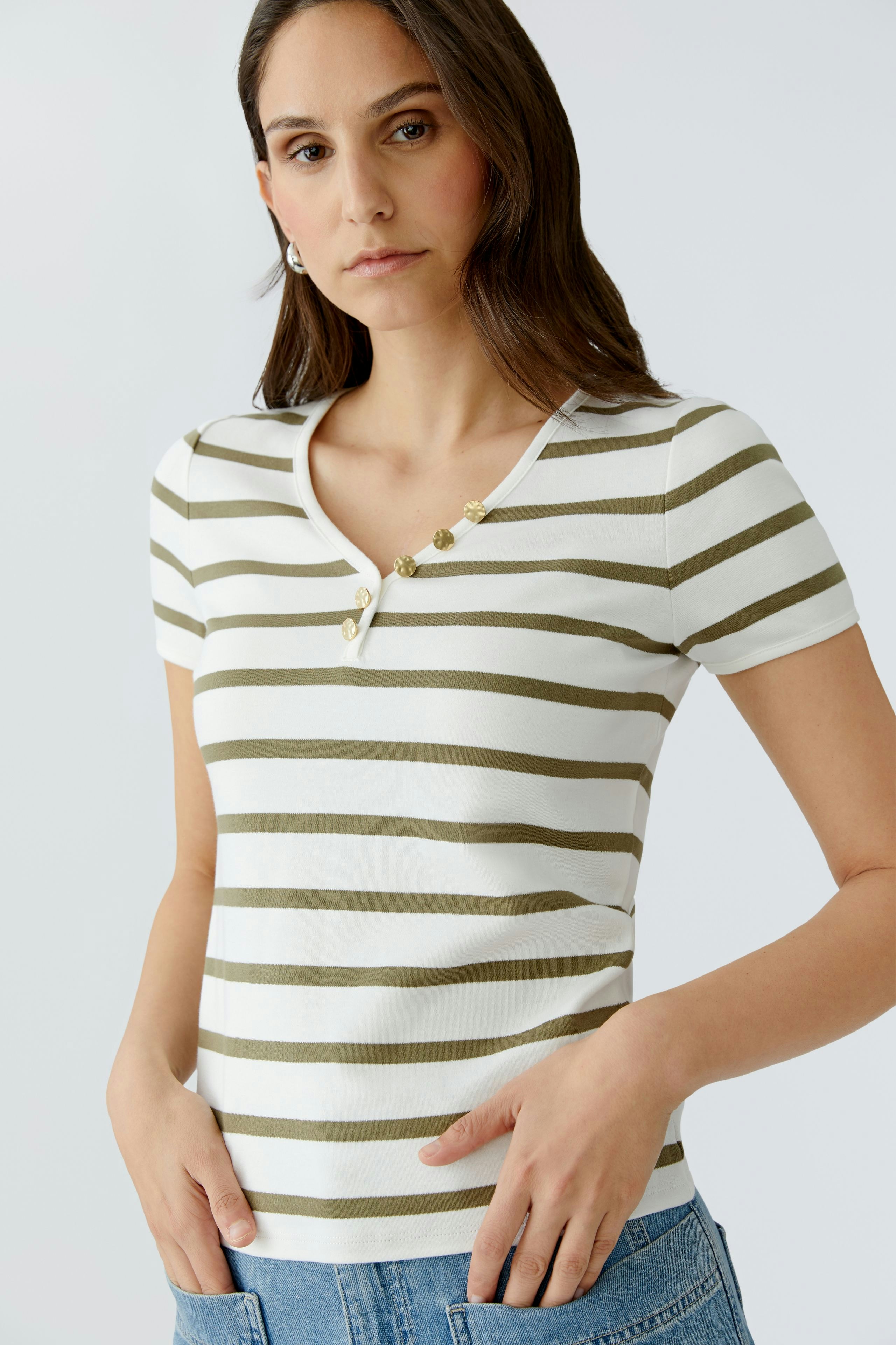 Casual women's T-shirt: Young woman in a striped tee with buttons, posing confidently.