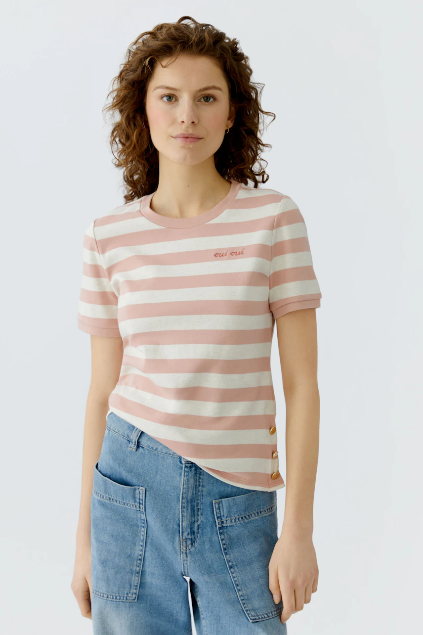 Casual women's T-shirt: Young woman in a pink and white striped tee with button details.