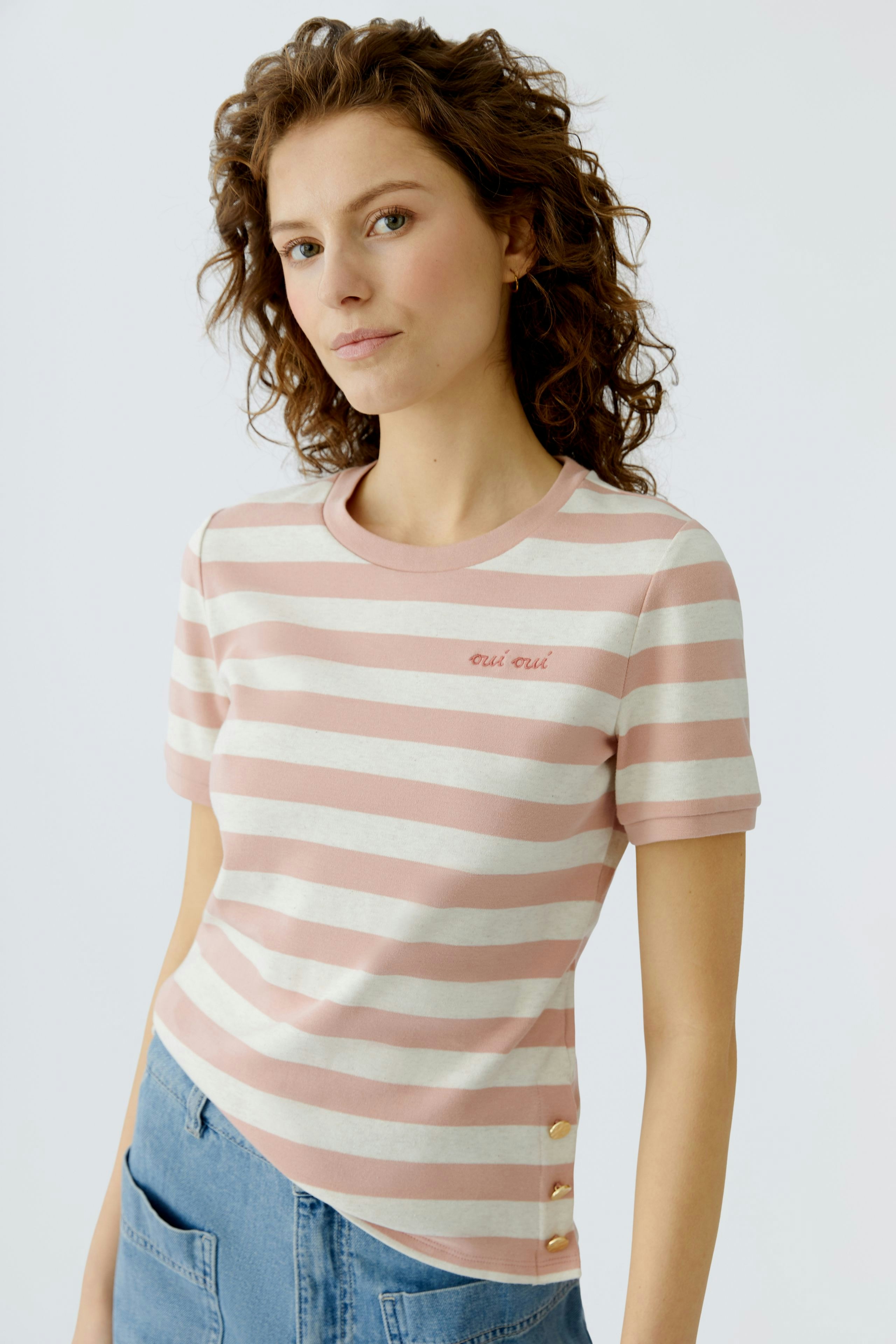 Casual women's T-shirt: Young woman in a pink striped tee with buttons, styled effortlessly.